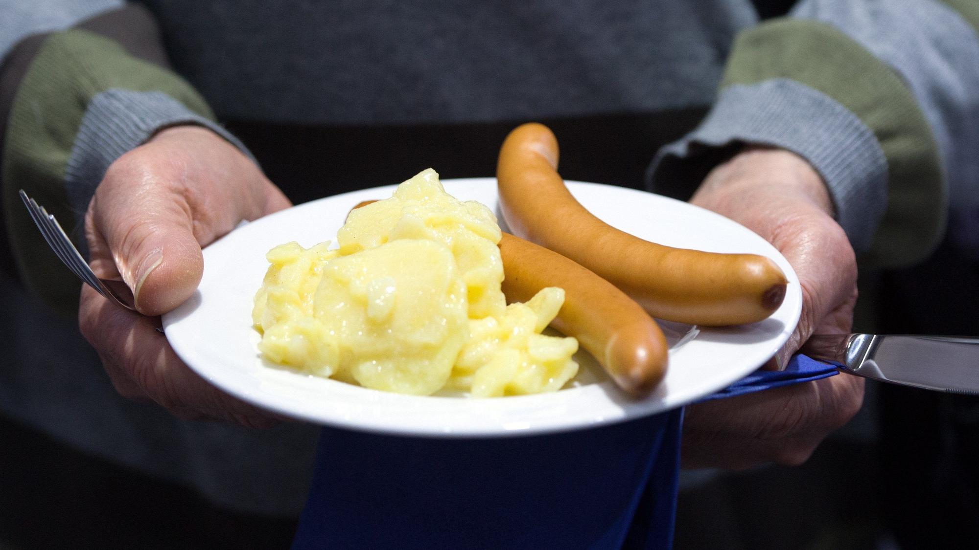Würstchen mit Kartoffelsalat liegen auf einem Teller.