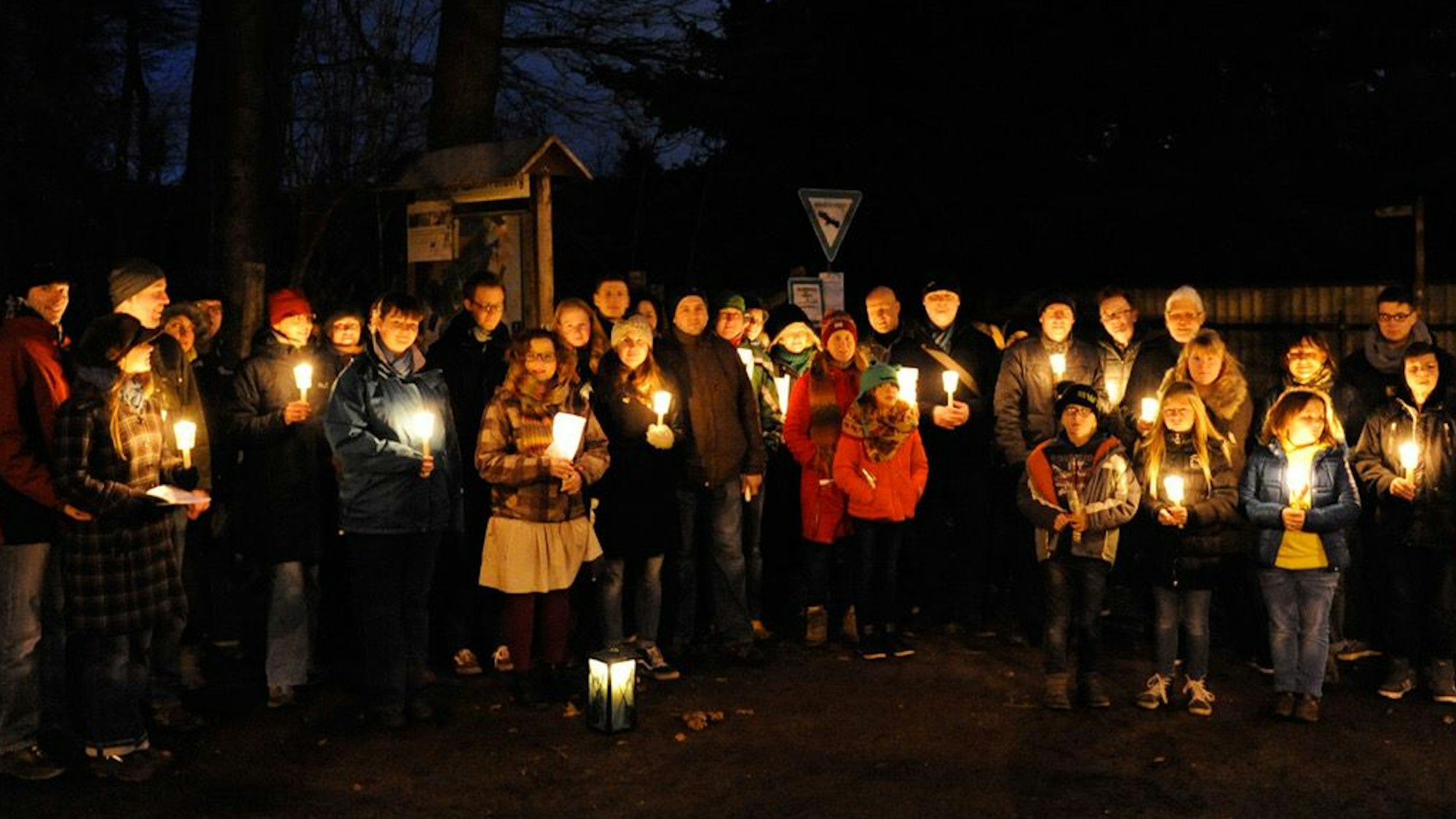 Zu sehen sind die Teilnehmer der Wanderung, die Kerzen in den Händen halten.