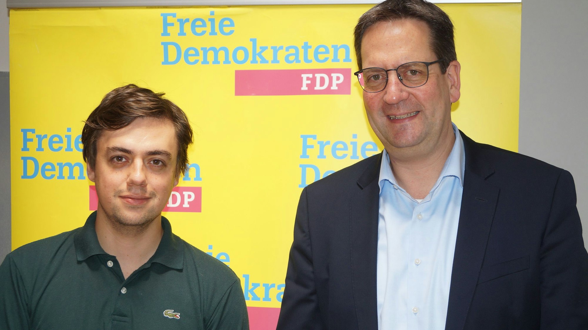 Frederik Schorn und Markus Herbrand stehen vor einem FDP-Banner.