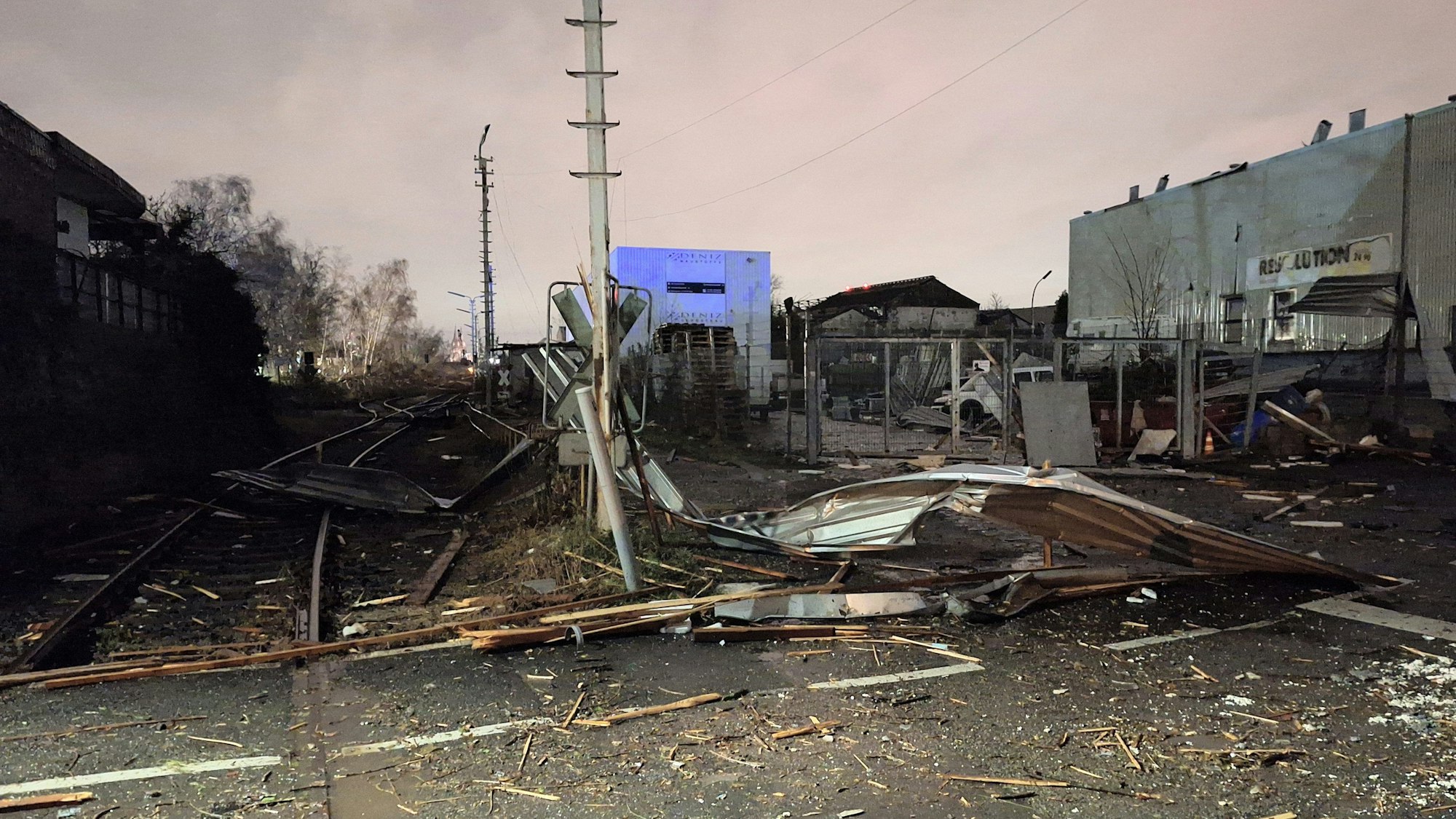 Ein Bahnübergang in Köln ist nach schweren Sturmböen und Regen durch Sturmtief Zoltan völlig zerstört. Mehrere abgerissene Teile blockieren die Straße und die Schienen.