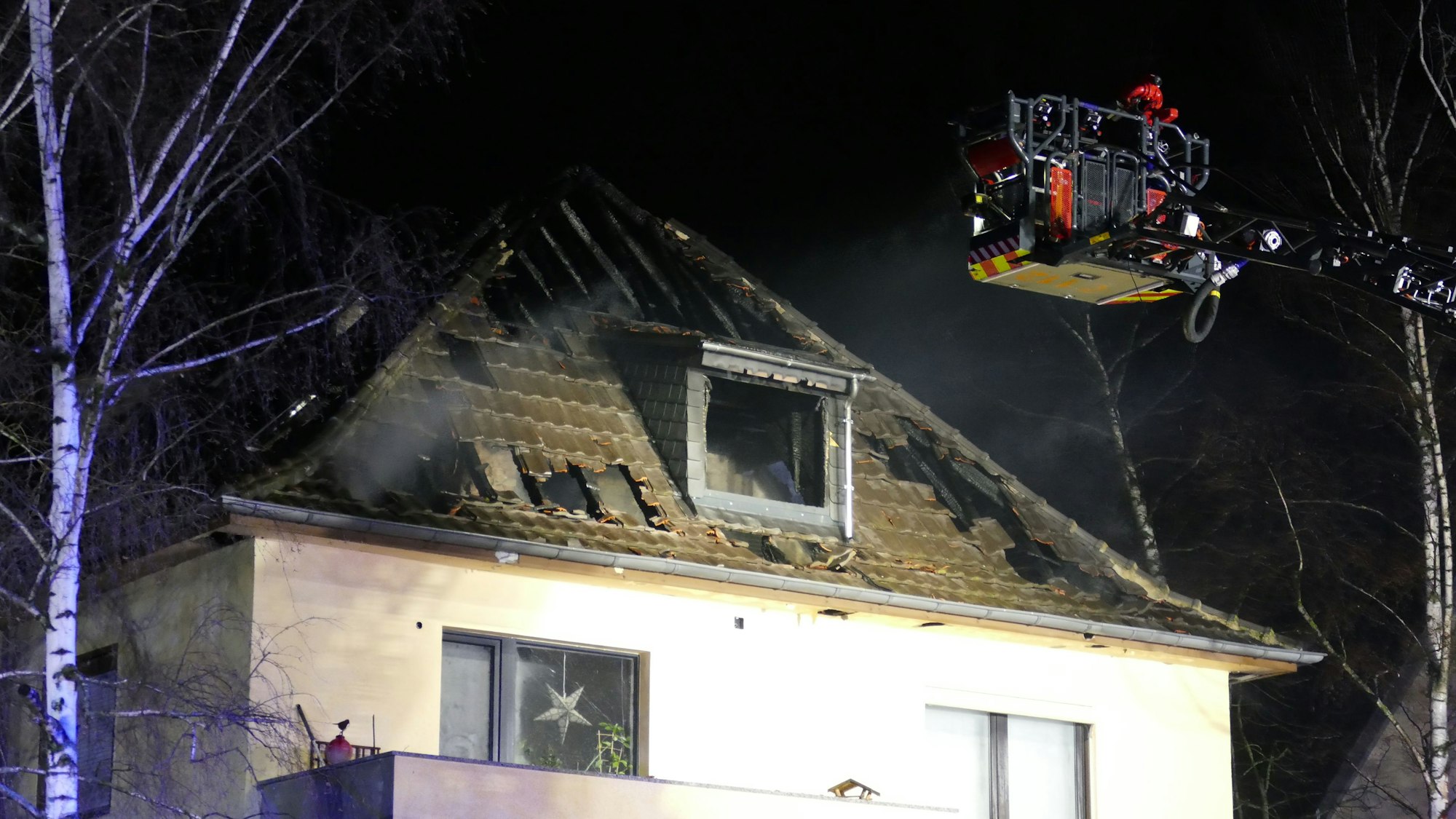 Ein Feuerwehrmann unter Atemschutz spritzt Wasser auf ein Haus.
