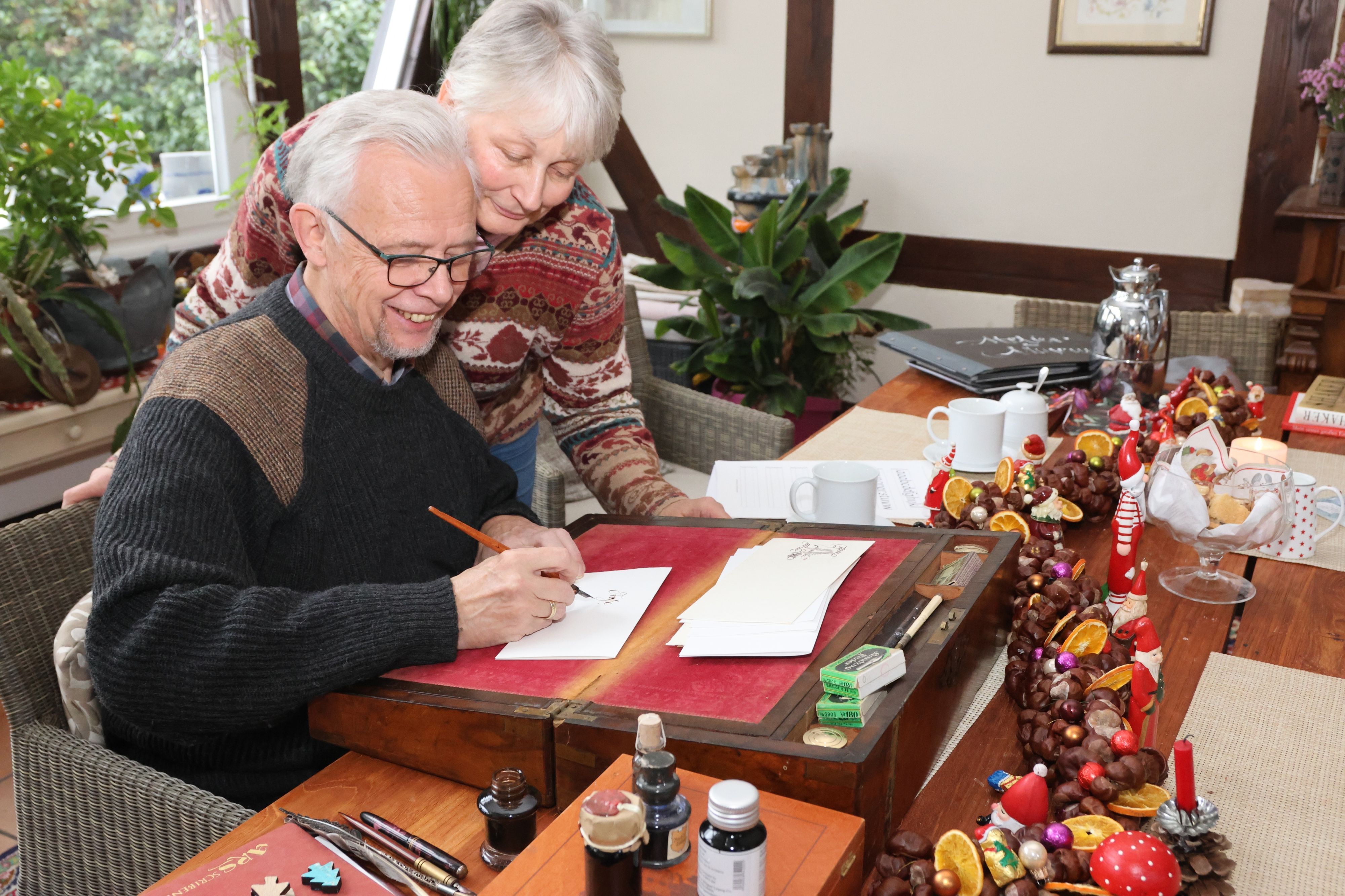 Ein Mann und eine Frau schreiben gemeinsam einen Weihnachtsbrief.
