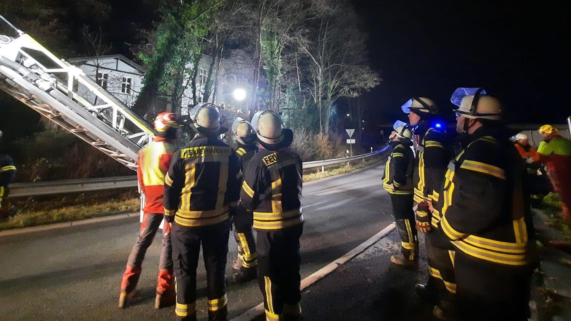 Feuerwehrleute stehen auf der Straße, eine Drehleiter ist ausgefahren.