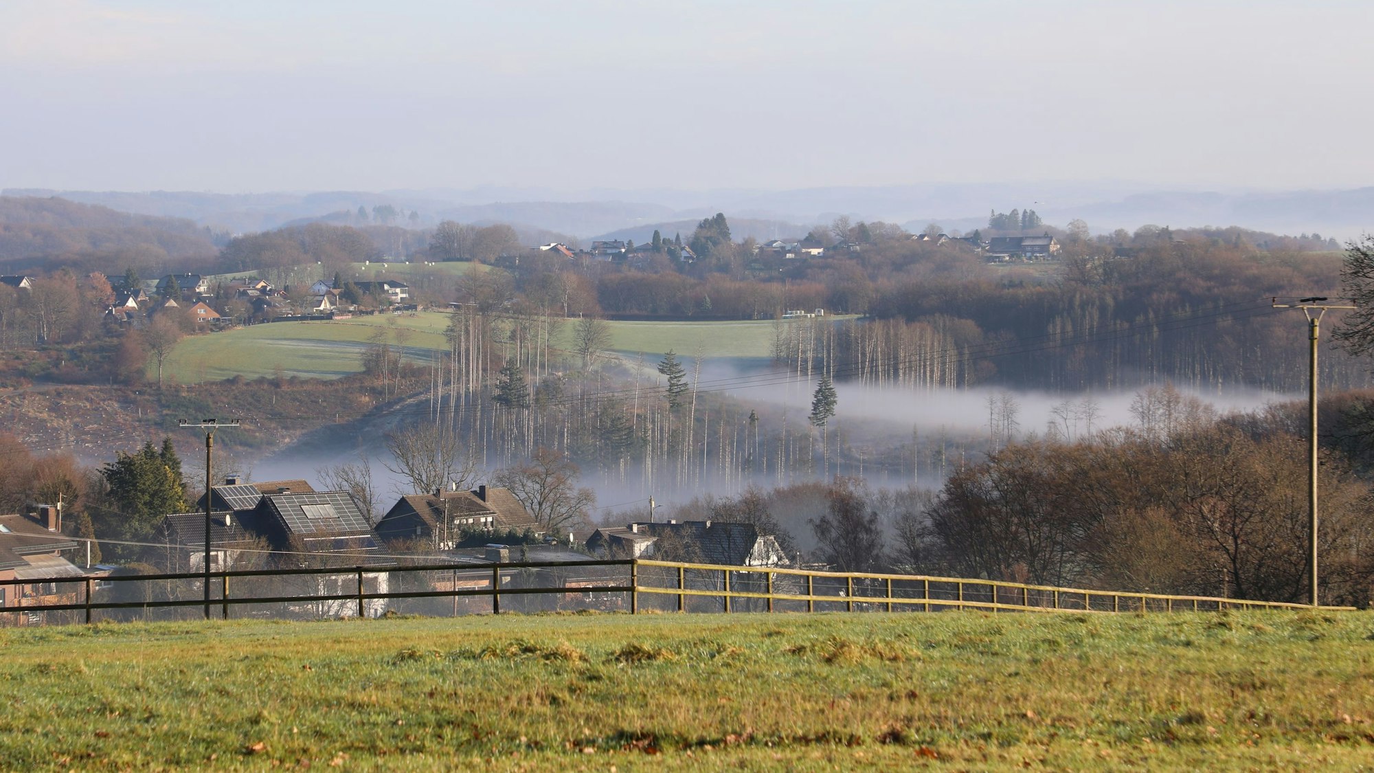 Sonne strahlt auf eine Winterlandschaft, in deren Tälern Nebel liegt.