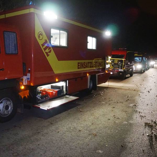 Mehrere Feuerwehrfahrzeuge stehen in der Dunkelheit auf einem Sammelplatz, von wo aus sie zu einem Einsatz im Ruhrgebiet aufbrechen.