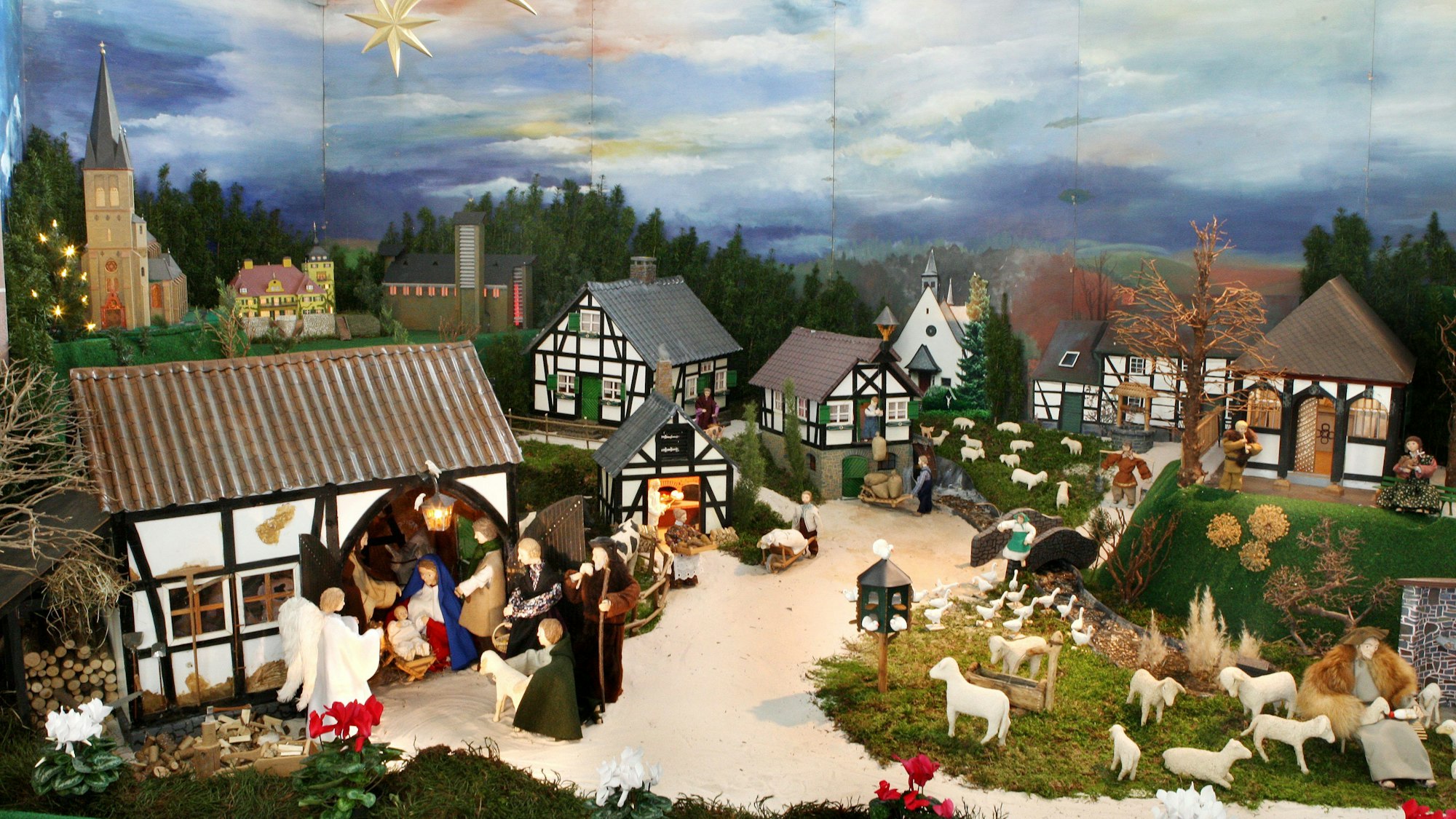 In einer Krippenlandschaft sind der Stall von Bethlehem, aber auch Gebäude aus Bergisch Gladbach wie die Kirche in Sand, Schloss Lerbach und die Rochuskapelle bei Sand zu erkennen.