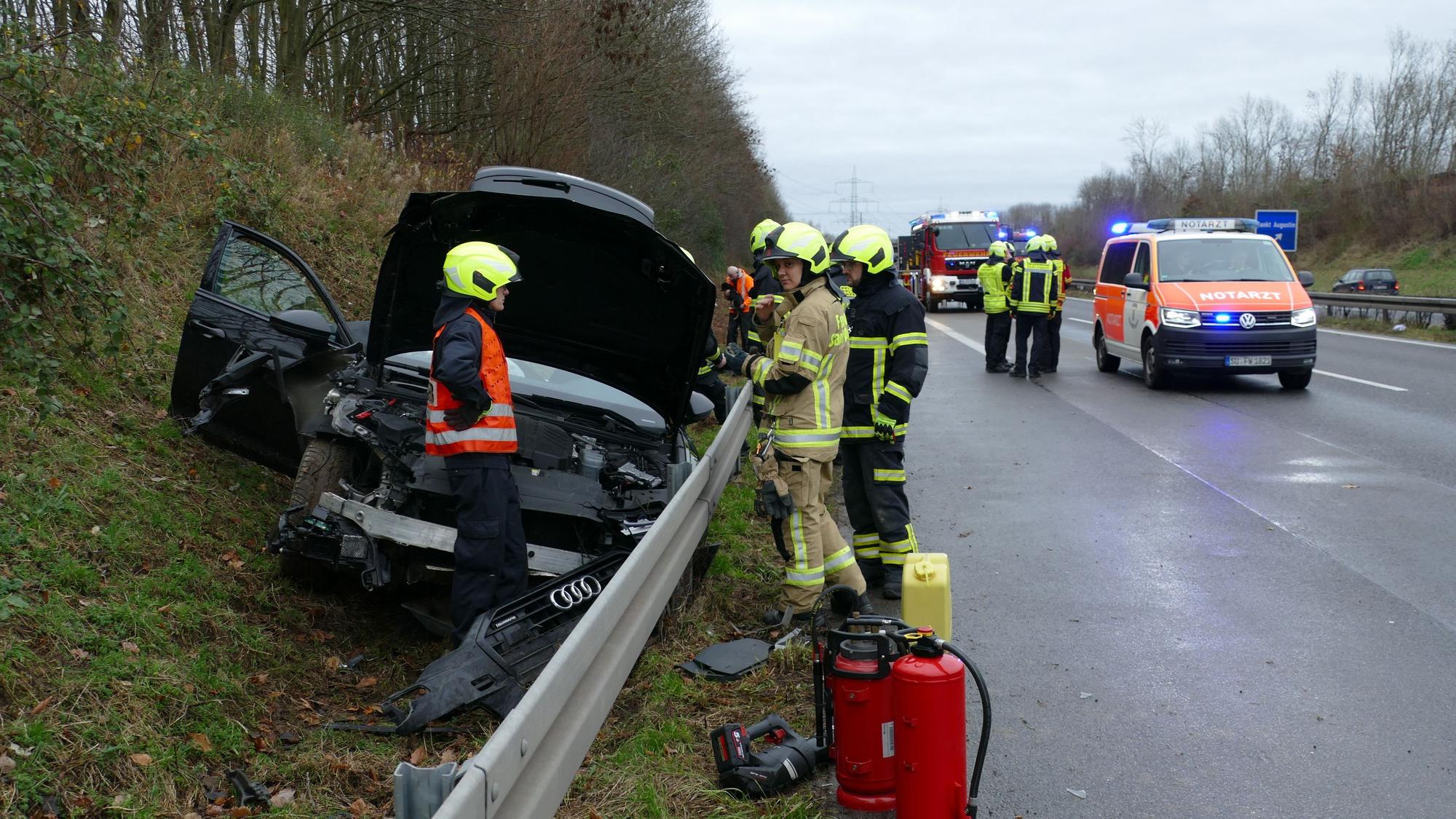 Ein schwarzer Wagen liegt hinter der Leitplanke, Feuerwehrleute stehen auf der Fahrbahn.