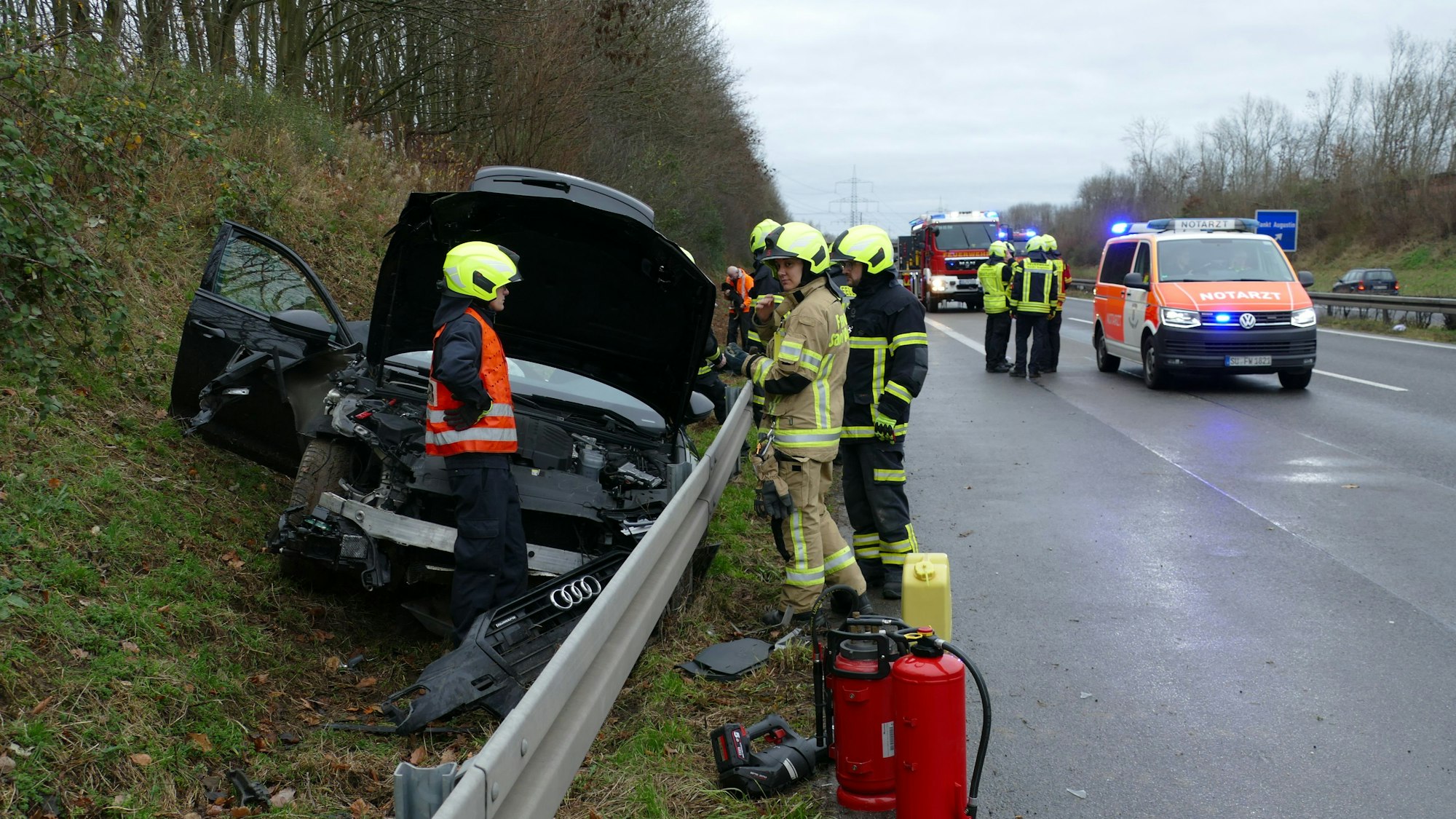 Ein schwarzer Wagen liegt hinter der Leitplanke, Feuerwehrleute stehen auf der Fahrbahn.
