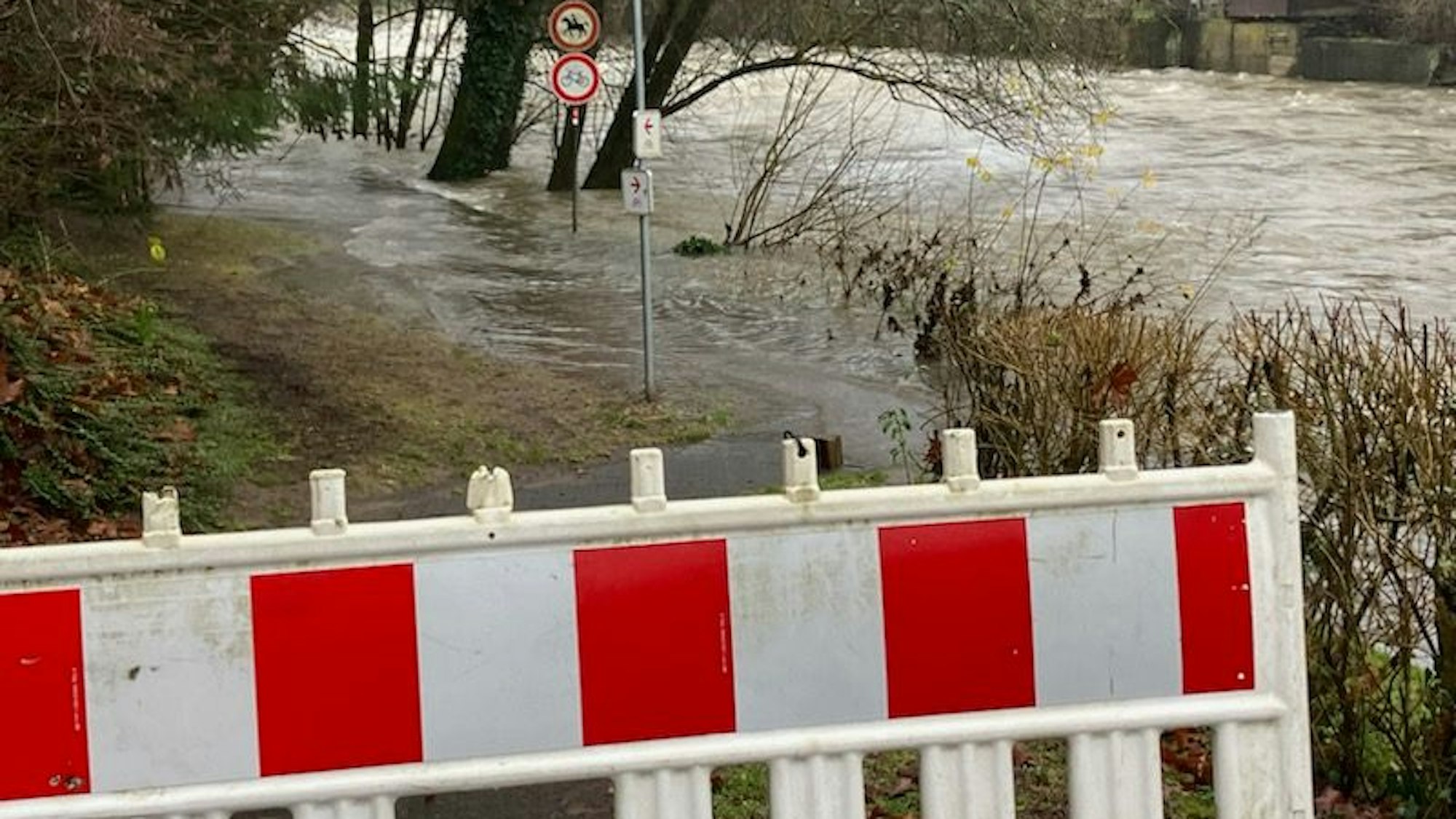 Die Agger überflutet einen Gehweg. Dieser ist abgesperrt.