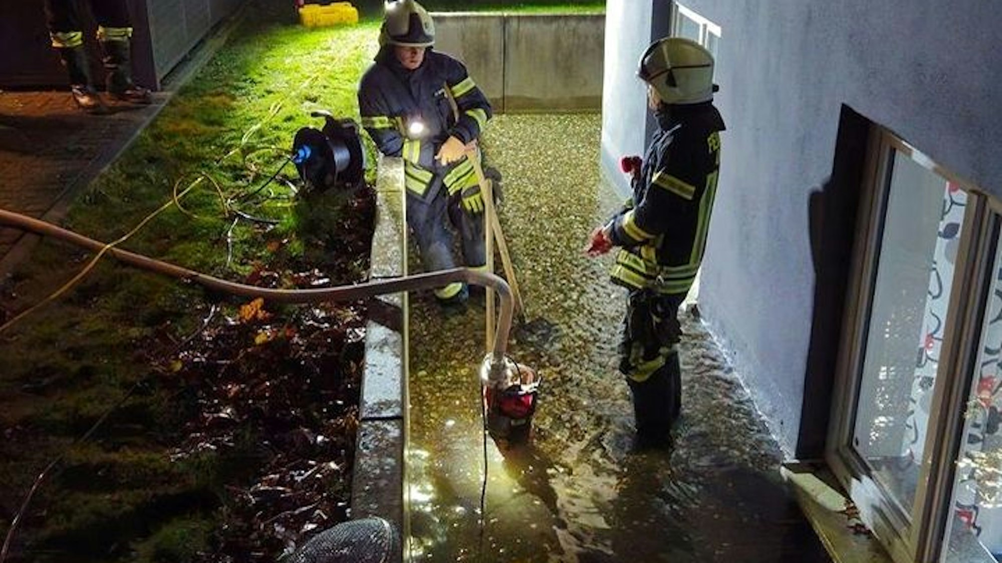 Feuerwehrleute Pumpen Wasser an einem Haus ab.