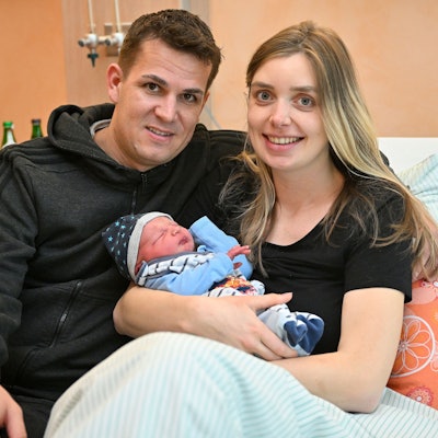 Marie Duske und Helge Hohl sitzen mit ihrem frisch geborenen Sohn in einem Bett im Evangelischen Krankenhaus Bergisch Gladbach.