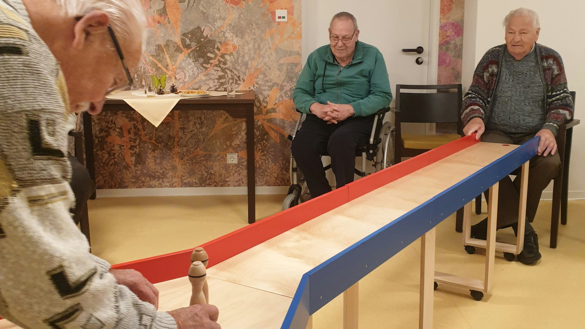 Mehrere Männer kegeln auf einer Tisch-Kegelbahn im DRK-Seniorenzentrum Wipperfürth.