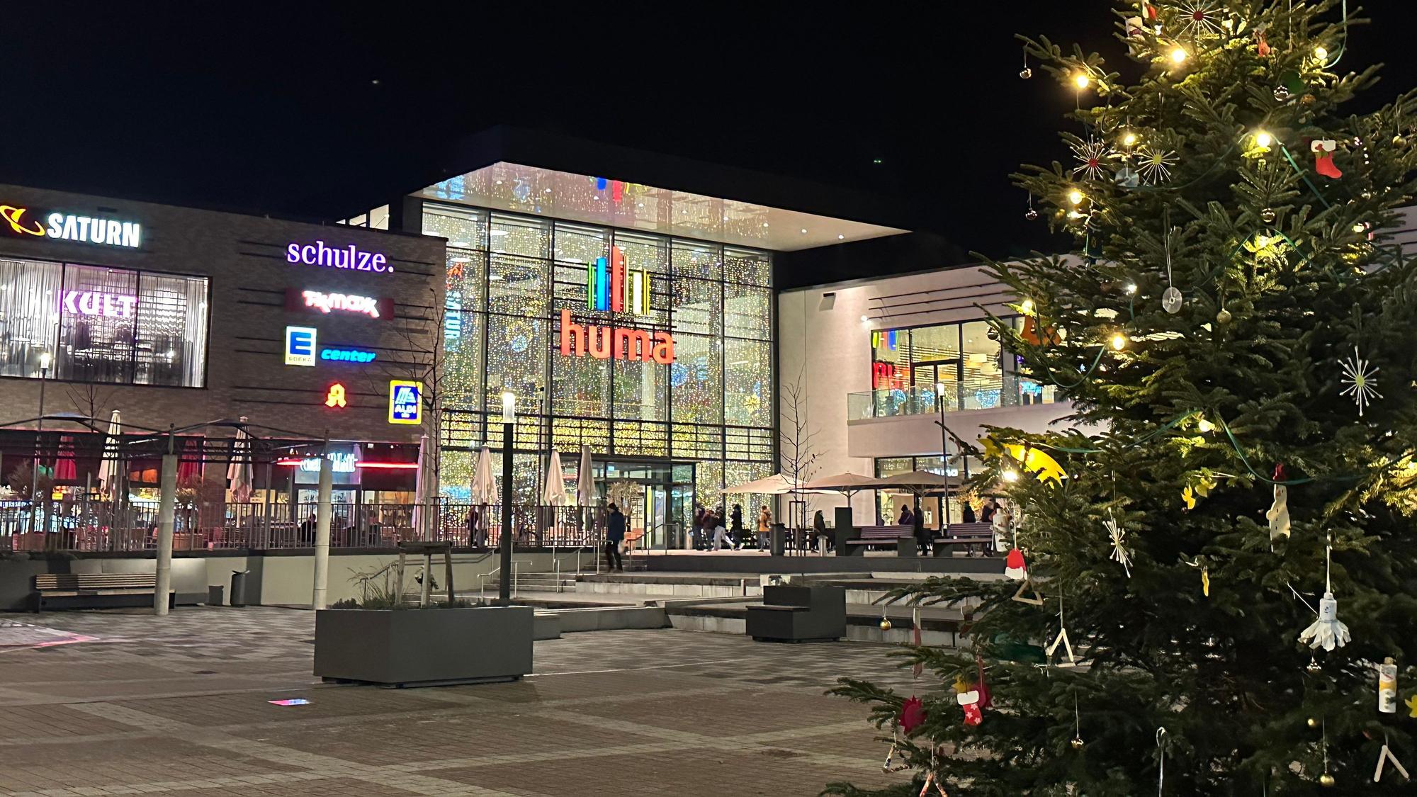 Blick auf das Huma-Einkaufszentrum mit einem beleuchteten Tannenbaum im Vordergrund.