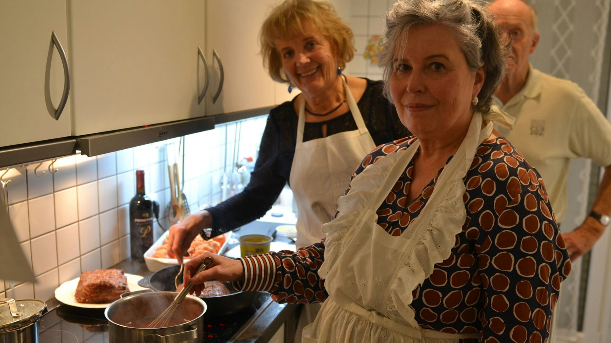 Marietheres Többens und zwei Hobbyköche arbeiten am Herd.