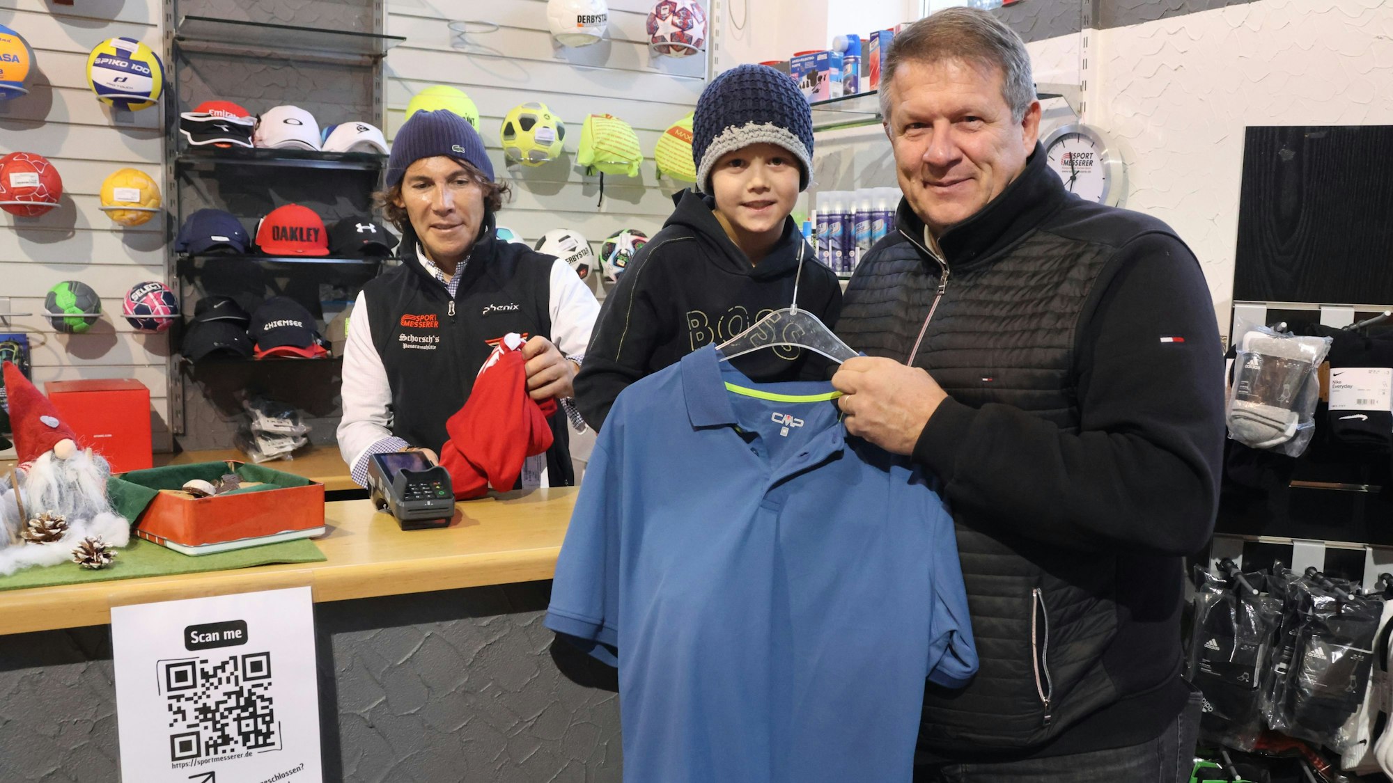 Ein Mann mit seinem Enkel beim Kauf eines Sport-T-Shirts.