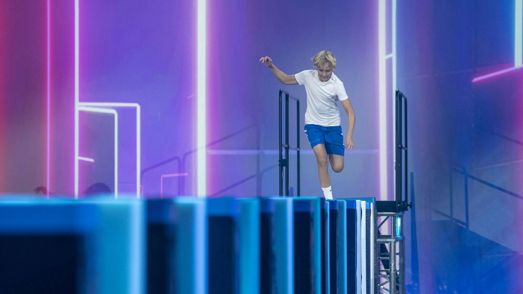 Auf dem Bild ist ein Junge zu sehen, der über Sportmatten läuft.