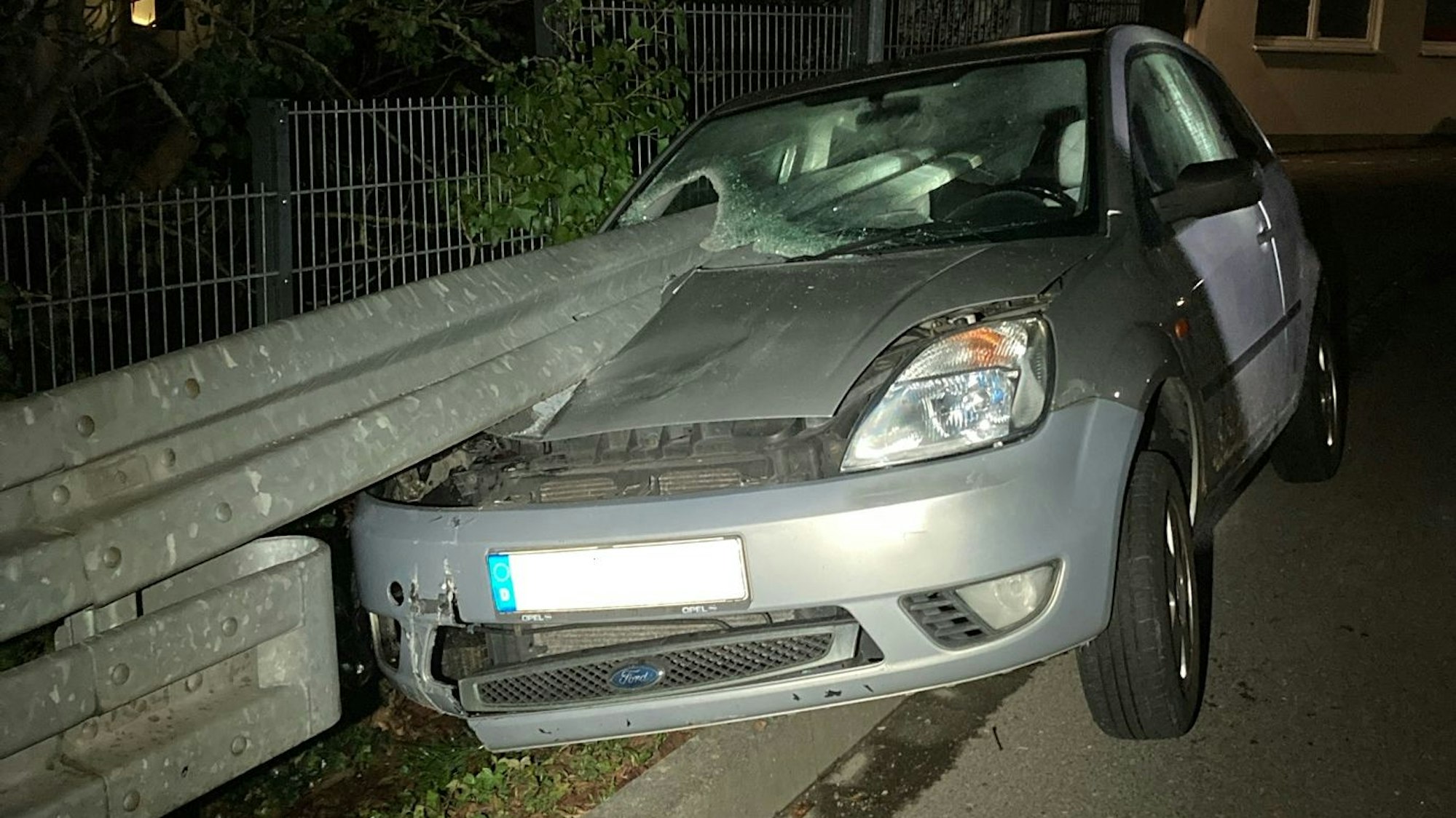 Ein Ford Fiesta an einer Leitplanke. Die Leitplanke bohrt sich durch das Fenster des Autos auf der Beifahrerseite.