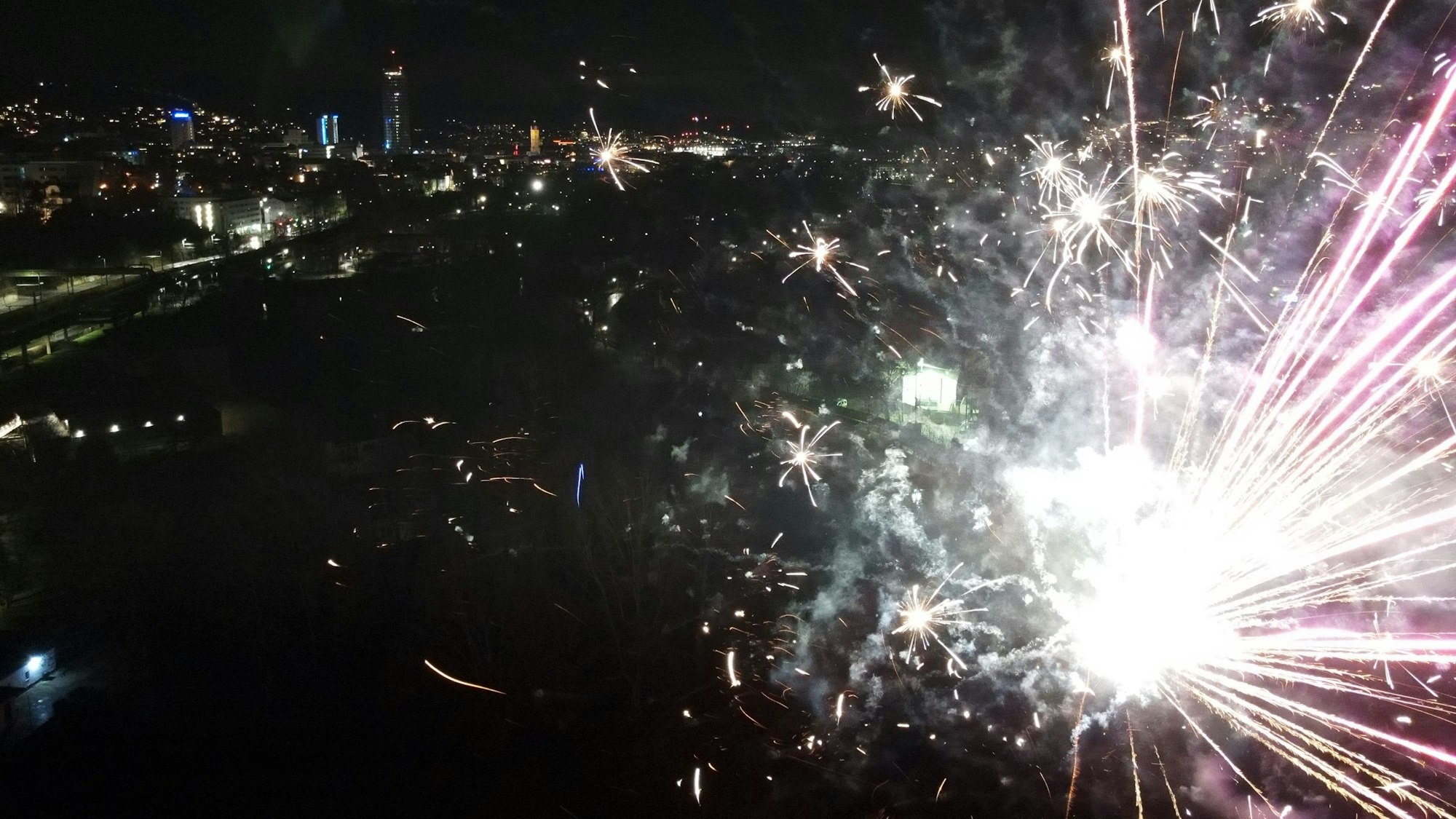 Thüringen, Jena: Explodierende Feuerwerksraketen sind am Nachthimmel über der Altstadt zu sehen. (Aufnahme mit einer Drohne)