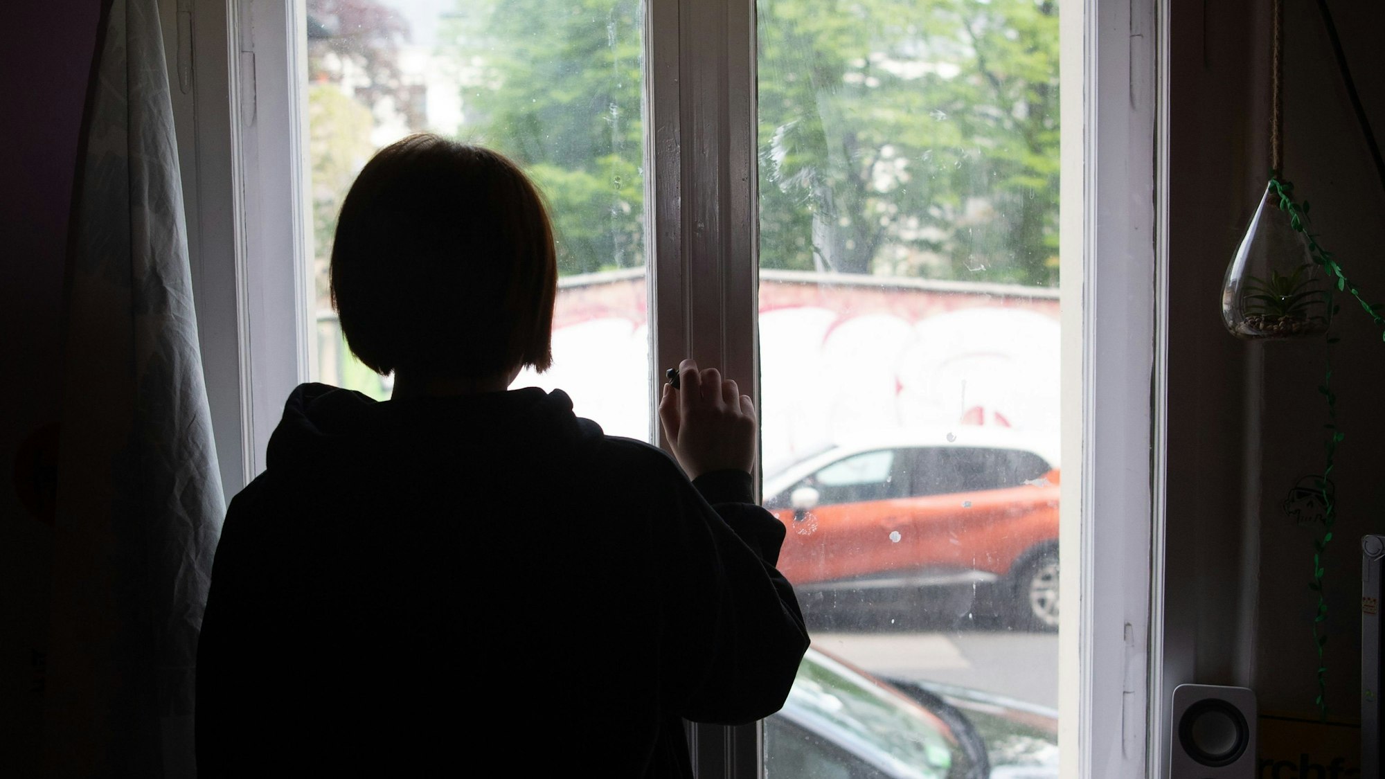 Eine Jugendliche blickt aus einem Fenster.