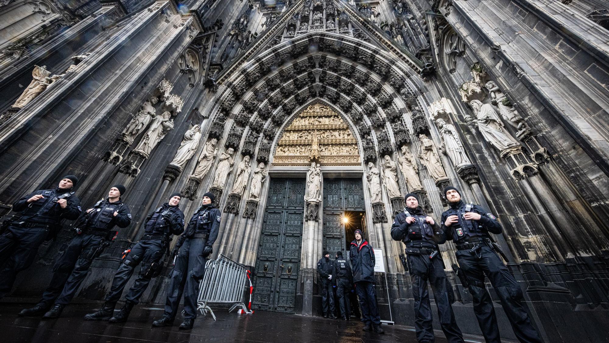 Mehrere Polizisten stehen vor dem Eingang des Doms.