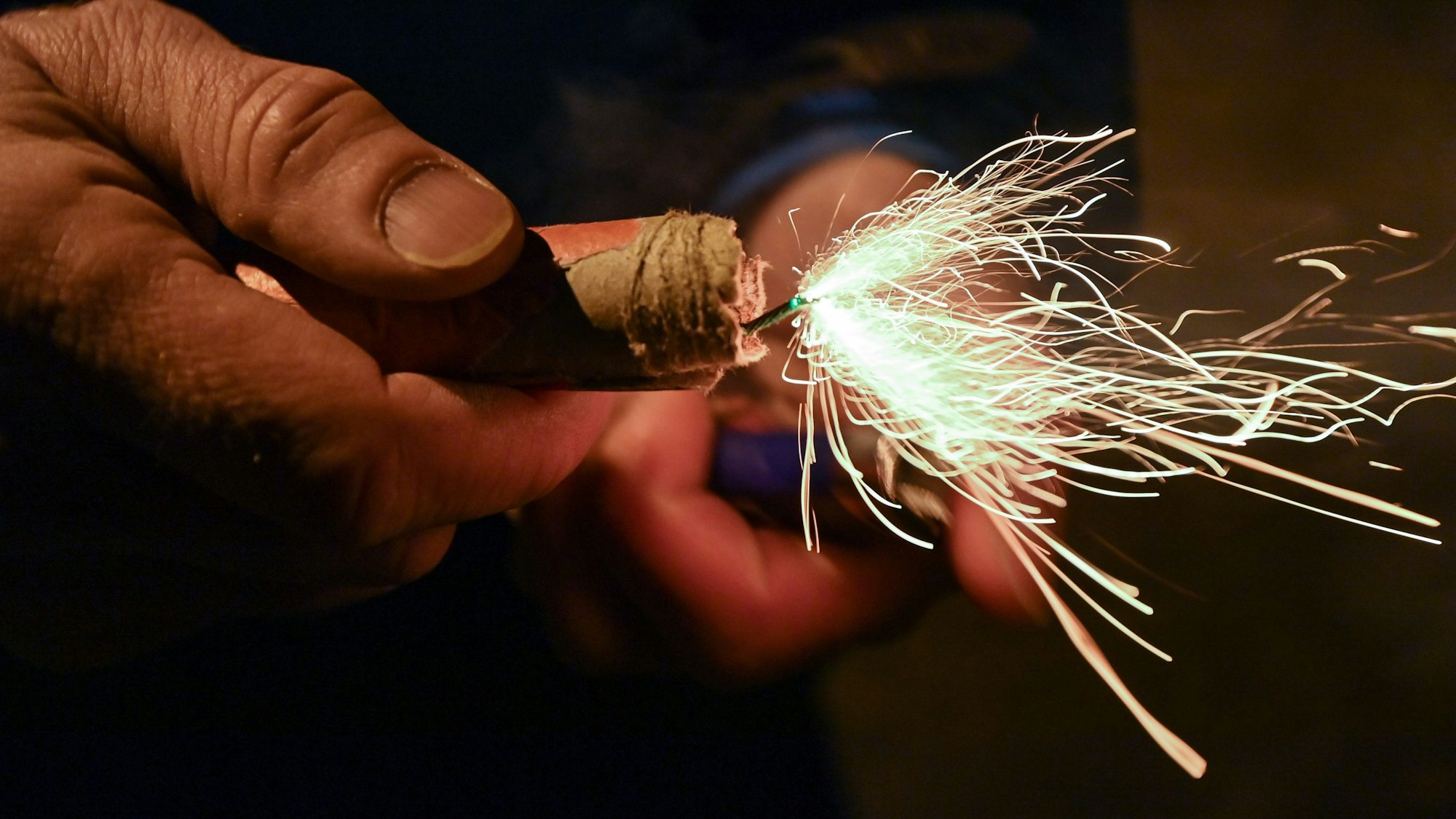 Eine Person hält einen angezündeten Böller in der Hand.