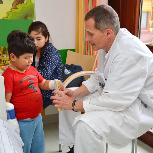 Das Foto zeigt einen Arzt und zwei Kinder