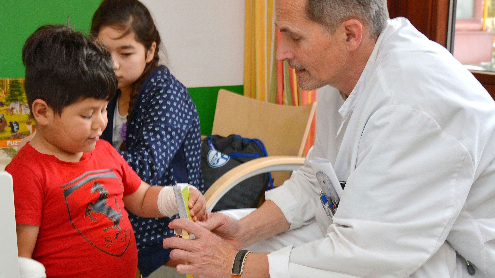 Das Foto zeigt einen Arzt und zwei Kinder