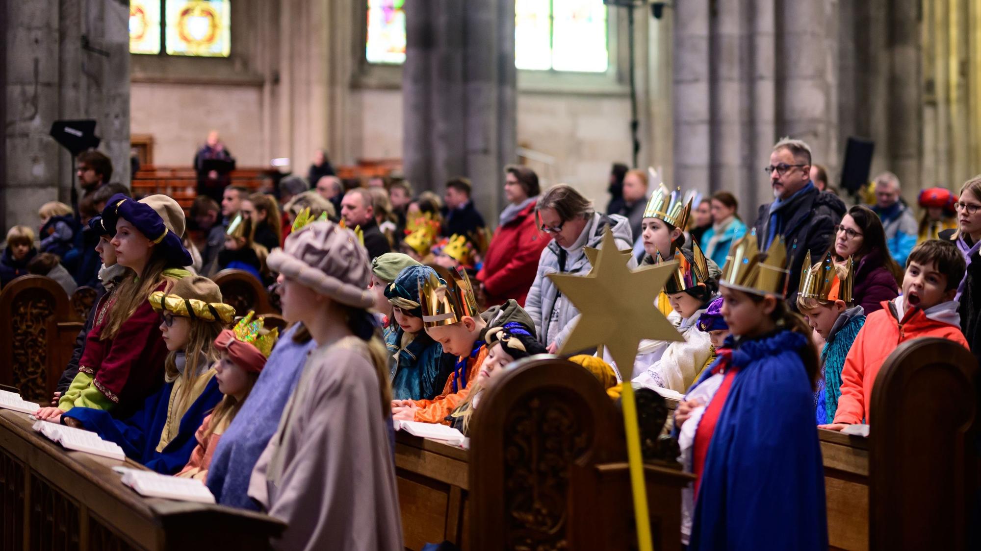 Sternsinger sitzen im Kölner Dom