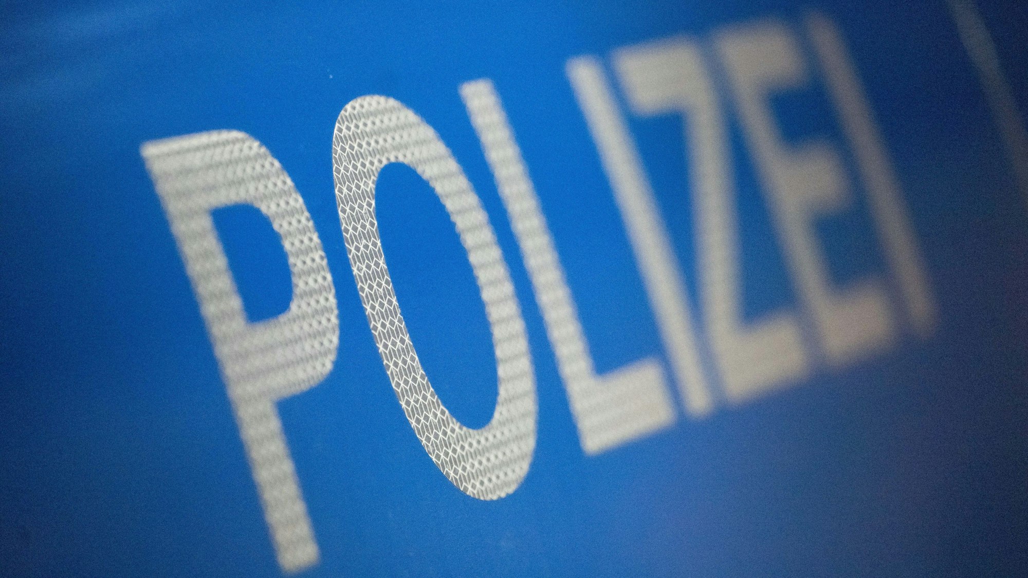 Das Wort Polizei ist im Rahmen eines Fototermins auf der Karosserie eines Polizeifahrzeugs zu sehen.