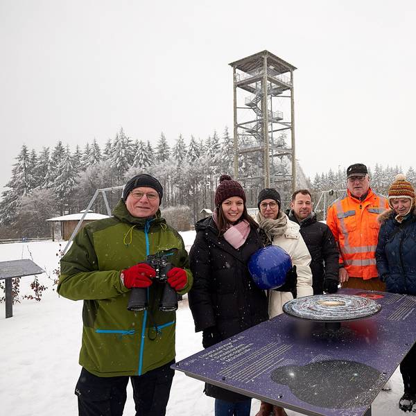 Die Vertreter der Gemeindeverwaltung, Touristiker und Gastgeber an einer der Info-Tafeln. Im Hintergrund des verschneiten Areals der Aussichtsturm am Weißen Stein.