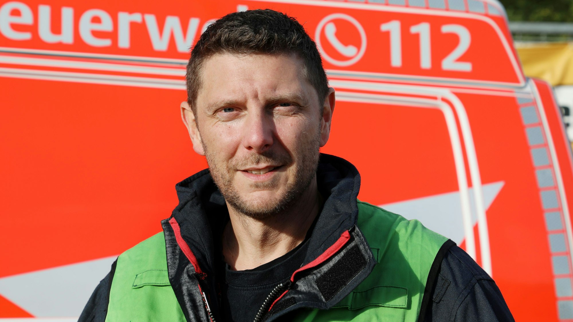 Rösraths Feuerwehrpressesprecher Björn Roth steht vor einem Feuerwehrfahrzeug.