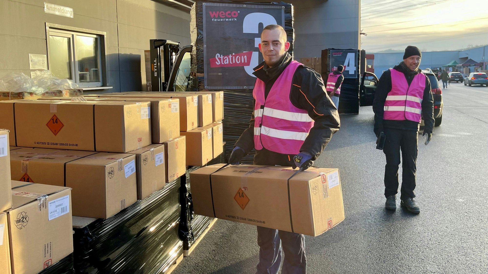 Ein junger Mann in Weco-Weste hält ein Paket.