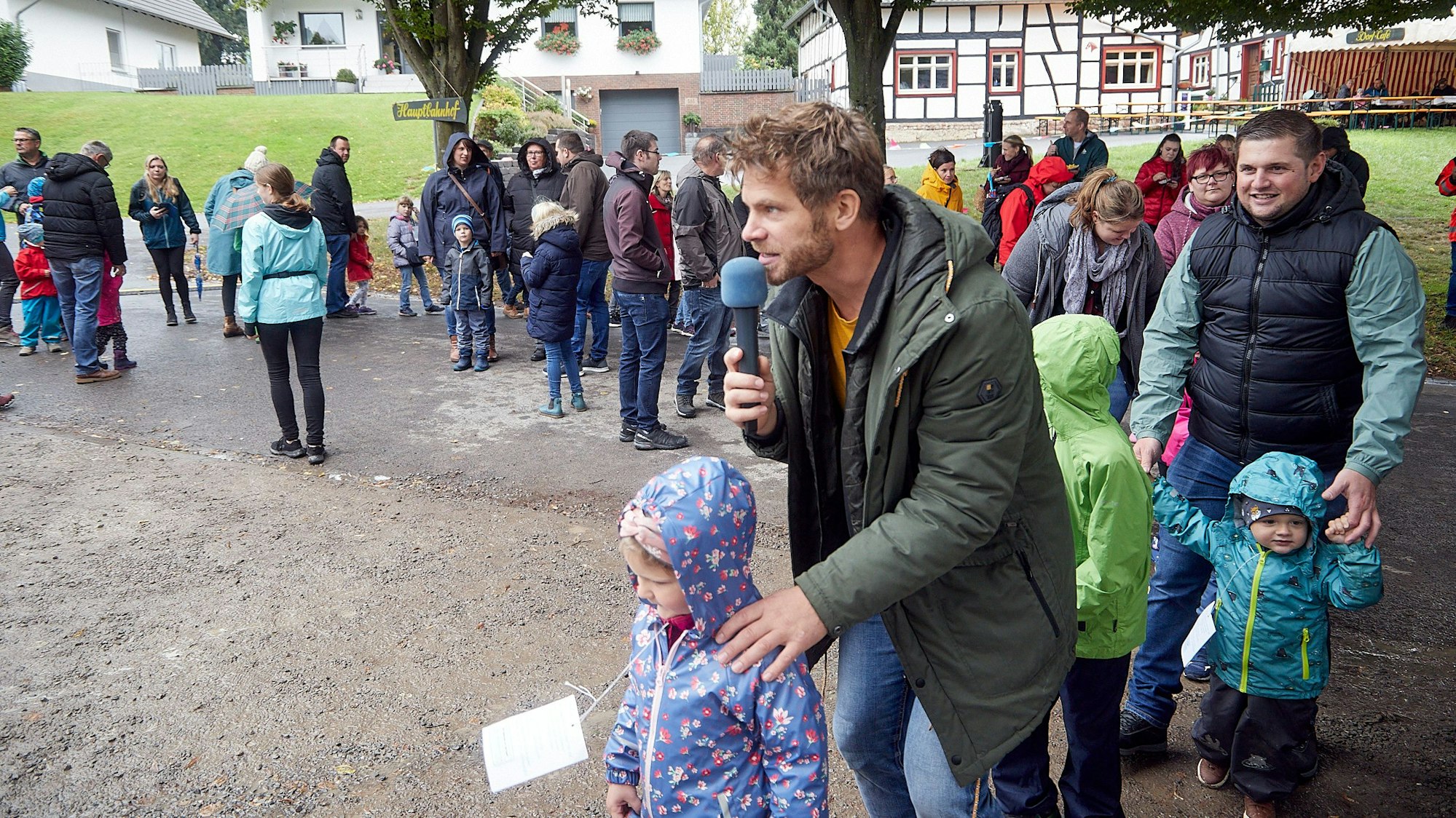 Der Kinderliedersänger Uwe Reetz hält ein Mikrofon in der Hand. Um ihn herum stehen einige Kinder mit ihren Eltern.