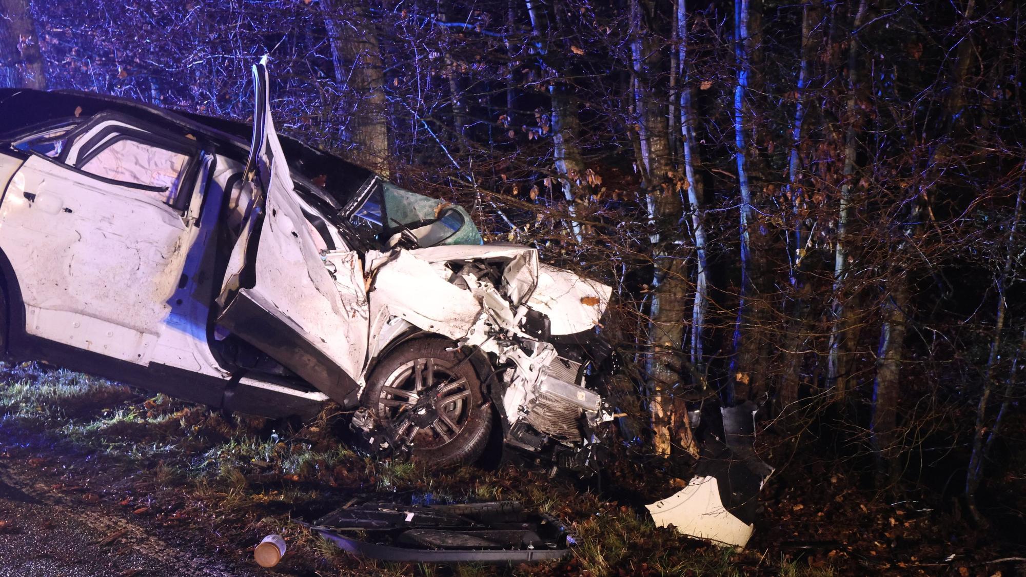 Ein total beschädigtes Auto steht vor einem Baum.