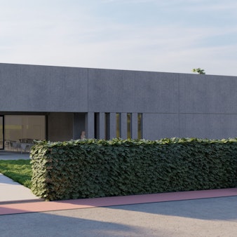 Das Bild zeigt einen modernen Bau, dessen Eingangsbereich mit viel Glas gestaltet ist. Vor dem Gebäude steht ein Stein mit der Aufschrift „Sharky Sportsclub“. An einer Hecke und einer Wiese vorbei führt der Weg zum Eingang.