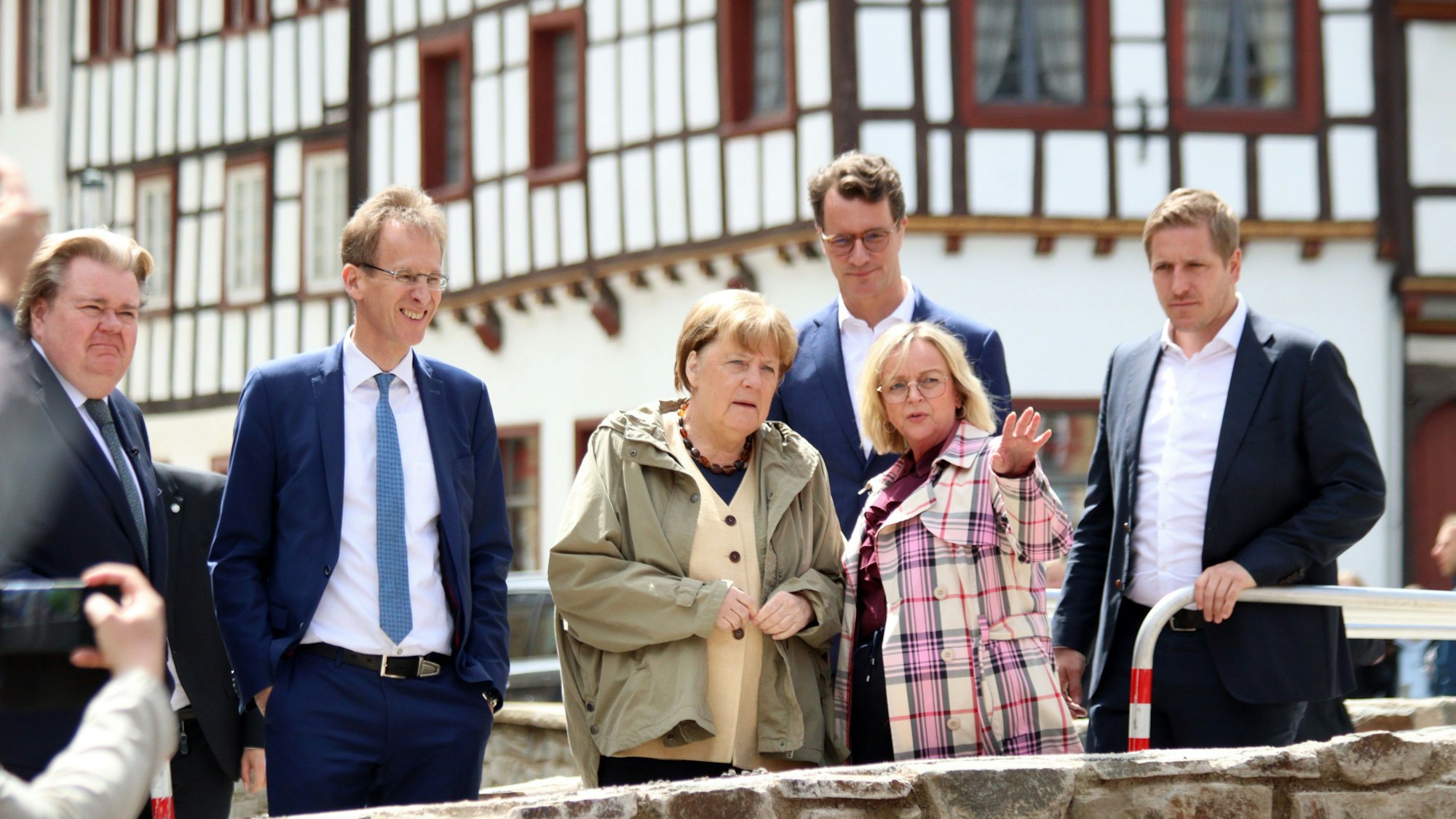 Das Bild zeigt den Landtagsabgeordneten Klaus Voussem, den Bundestagsabgeordneten Detlef Seif, Angela Merkel, NRW-Ministerpräsident Hendrik Wüst, Sabine Preiser-Marian (alle CDU) und Markus Ramers (SPD) auf einer Brücke in Bad Münstereifel.