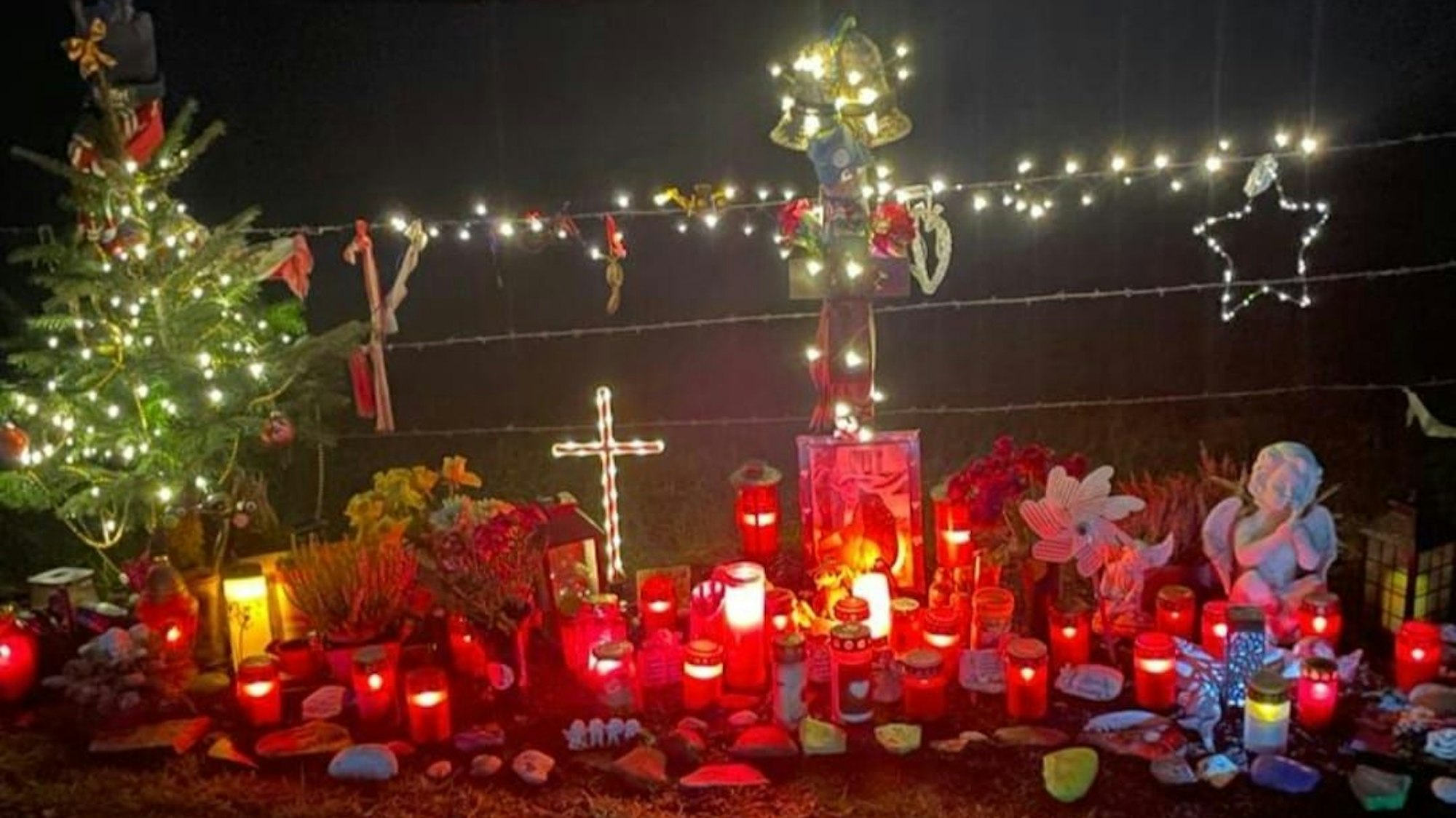 Kerzen leuchten im Dunkeln an einer Unfallstelle, an der ein 22-Jähriger aus Odenthal-Eikamp am 1. Januar 2023 ums Leben kam.