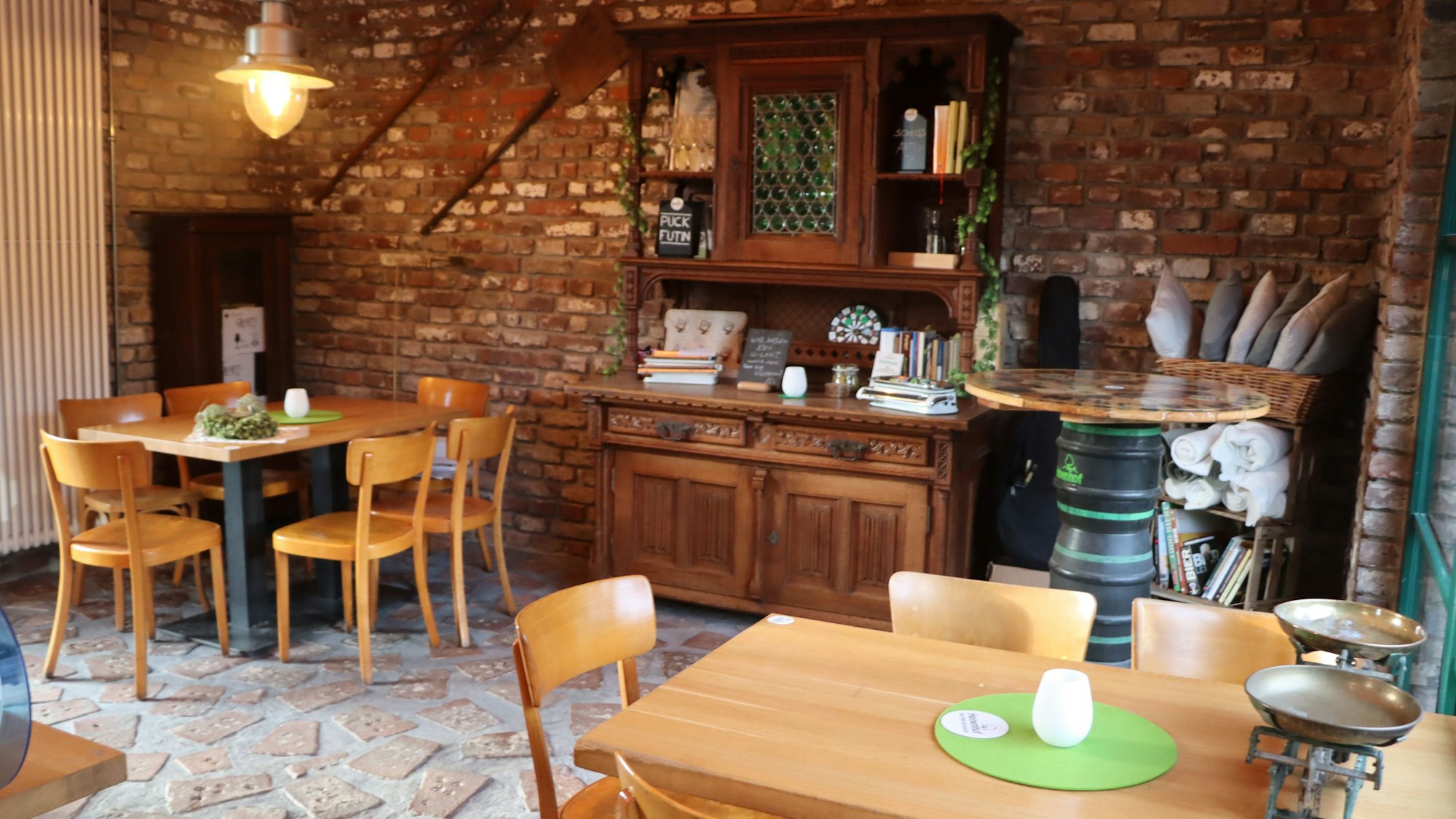 Zu sehen ist ein Raum mit Tischen, Stühlen und einem Schrank.