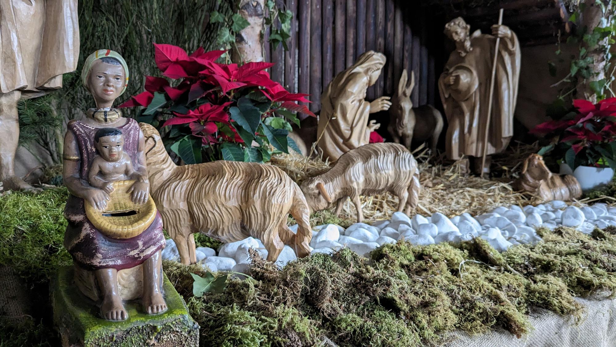 Eine Missionsspardose (li.), die eine dunkelhäutige Frau mit einem Kind auf dem Schoß darstellt, ist Teil der Kirchenkrippe der Pfarrkirche St. Martin in Nettersheim.
