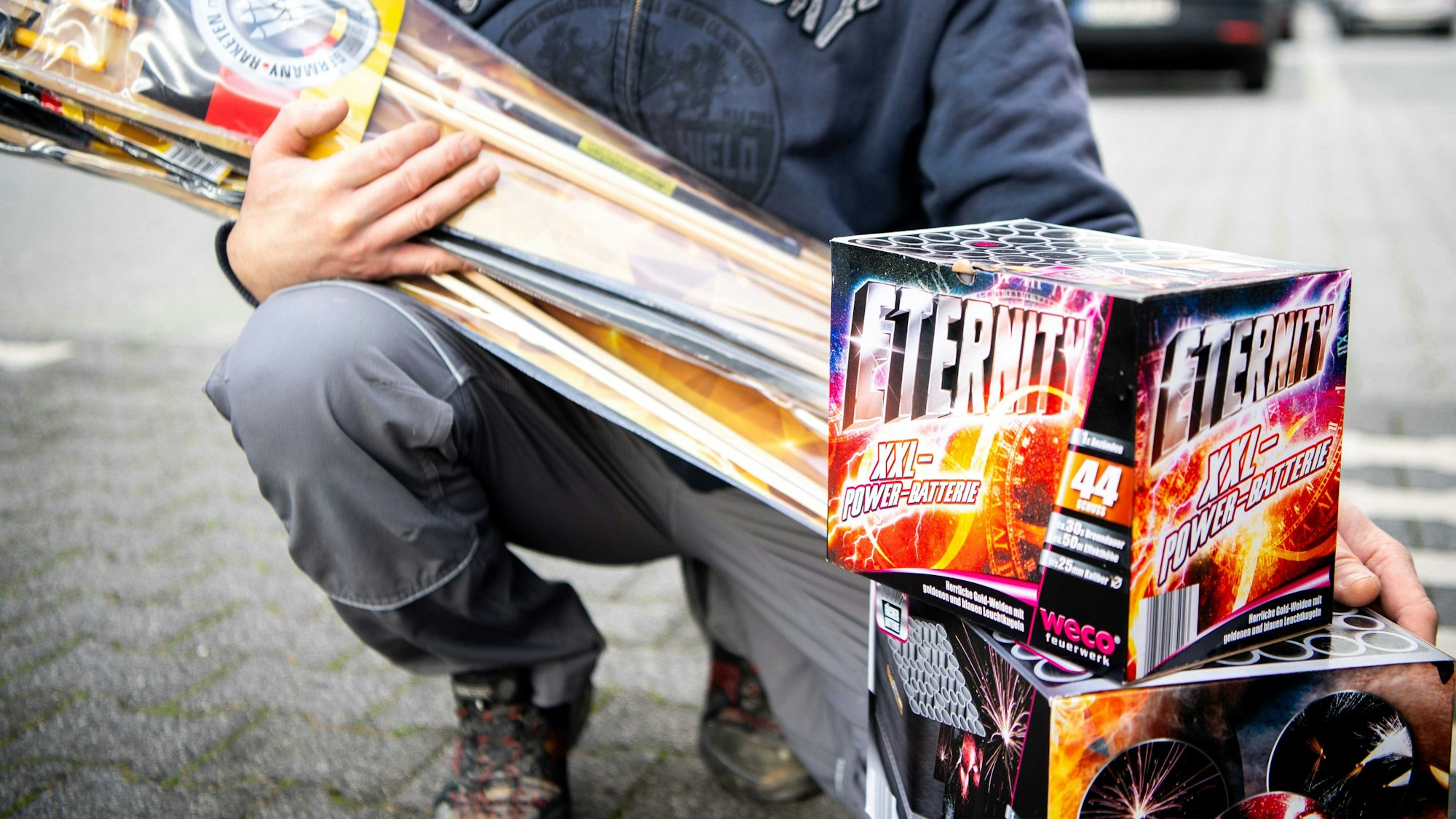 Ein Mann, dessen Gesicht nicht zu sehen ist, zeigt das Silvesterfeuerwerk, das er gekauft hat..
