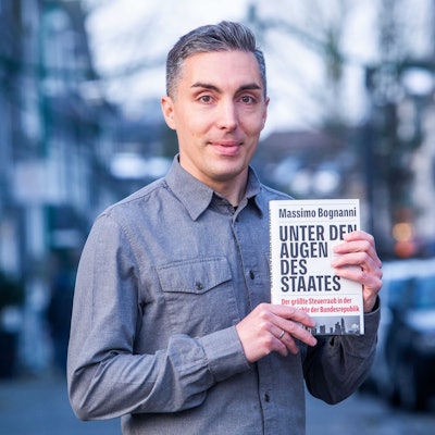 Das Foto zeigt Massimo Bognanni mit seinem Buch „Unter den Augen des Staates“.
