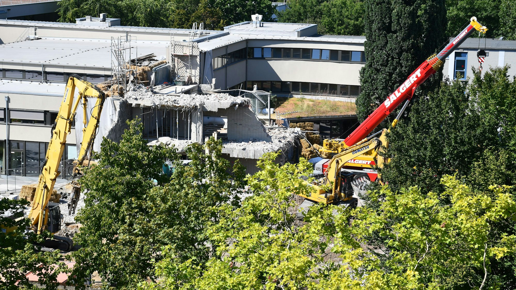Mit schwerem Baugerät wird ein Gebäudeteil einer Schule abgebrochen.
