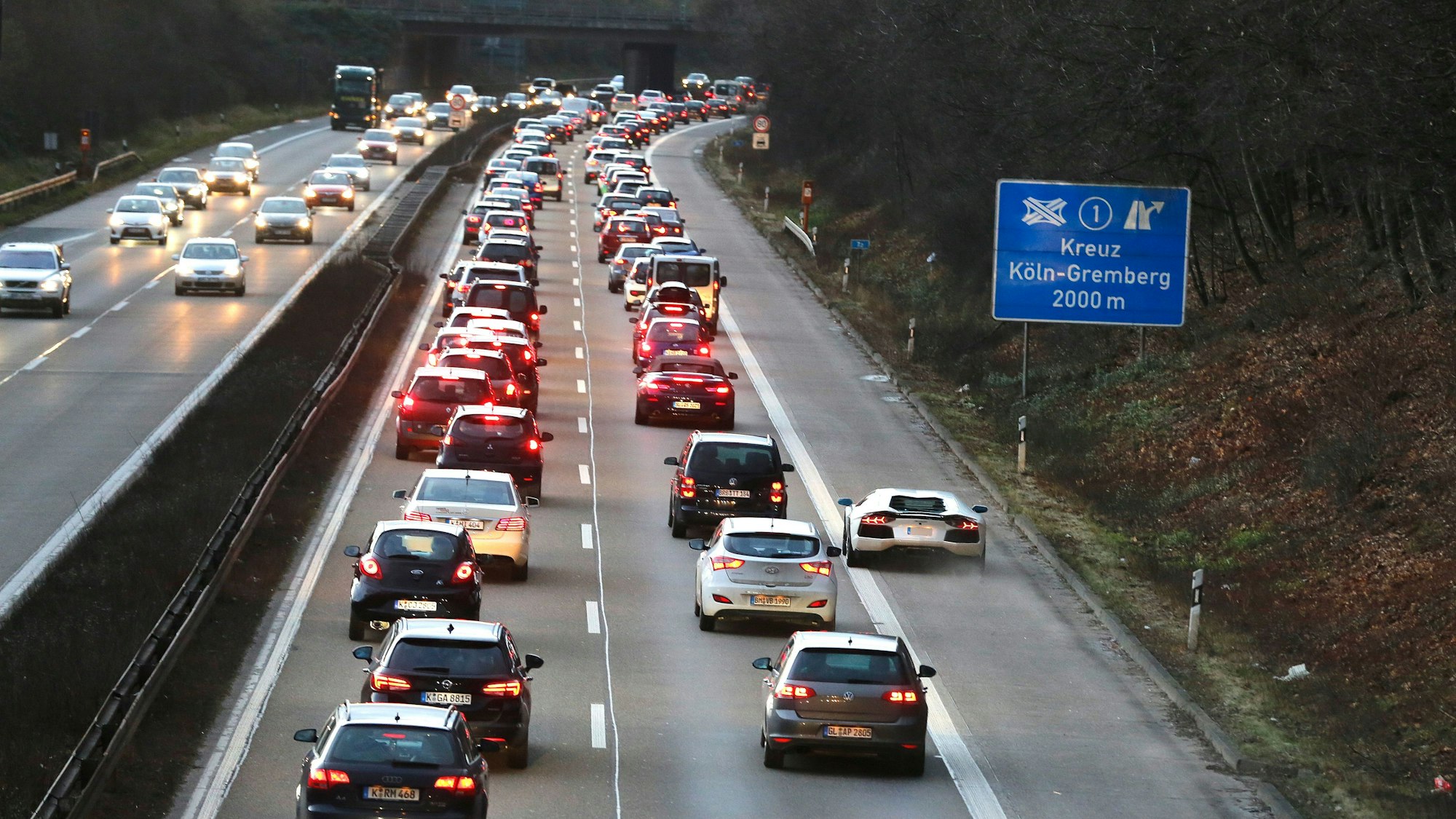Verkehrsstau auf der Autobahn A59 in Richtung Köln, ein weißer Sportwagen überholt rechts auf dem Standstreifen.