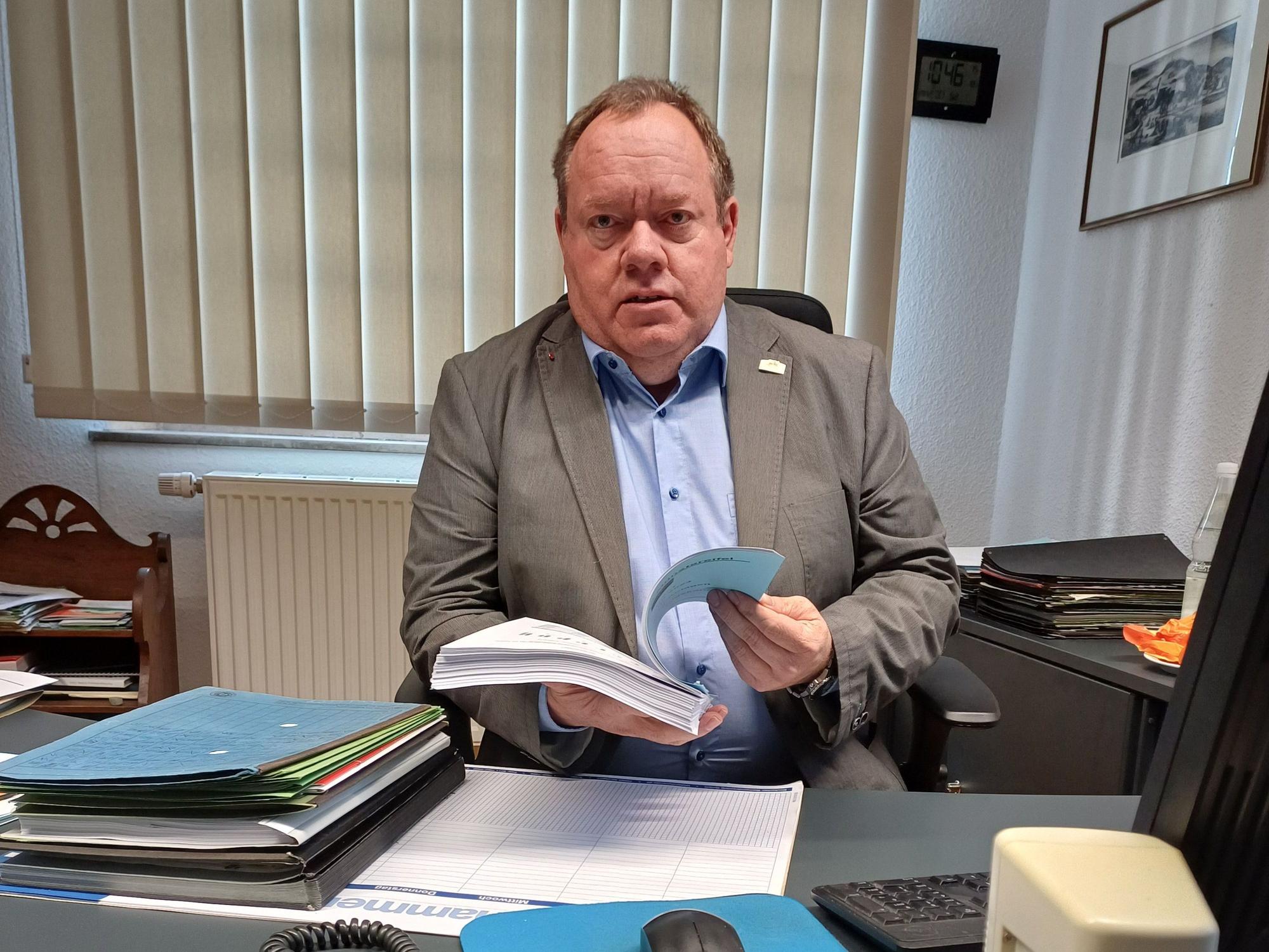 Kurt Reidenbach sitzt an seinem Schreibtisch und hält den Vorentwurf zum Haushalt 2024 in den Händen.