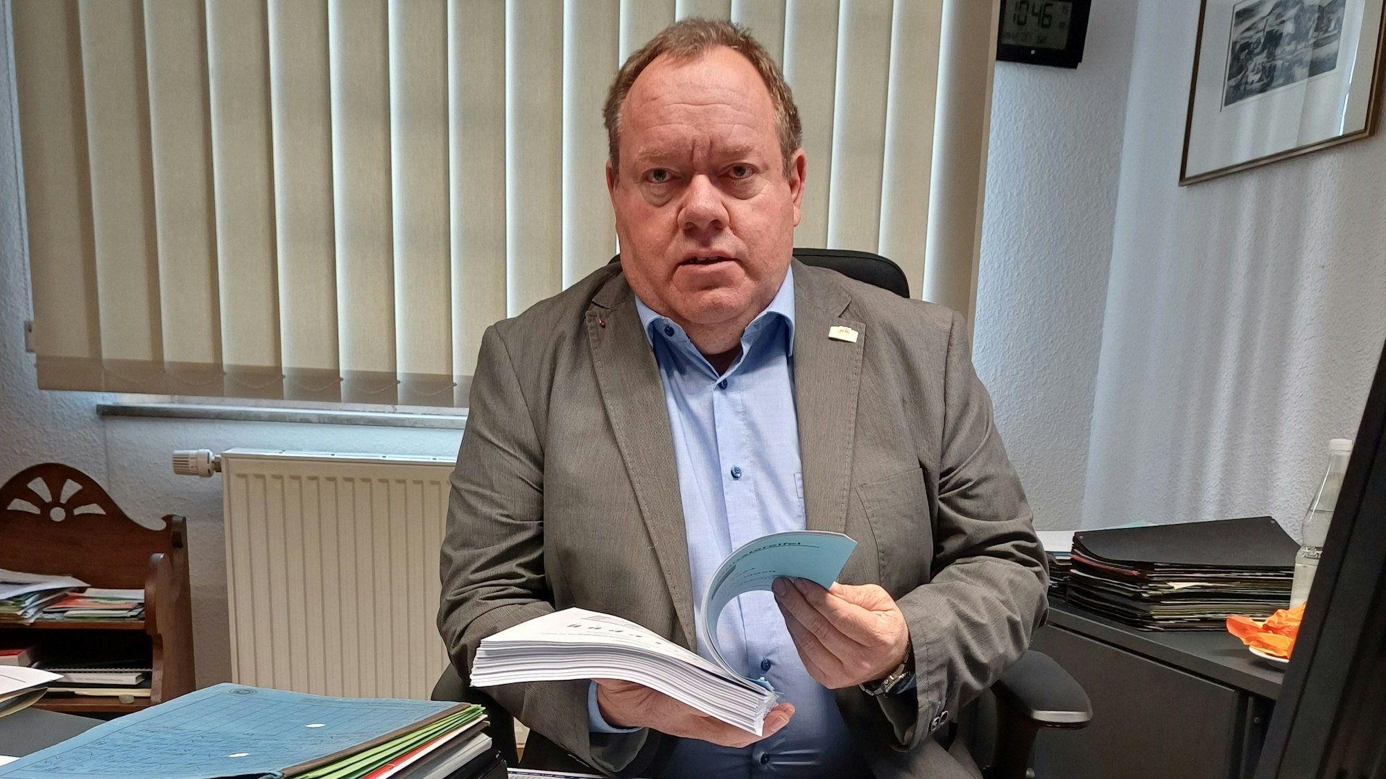 Kurt Reidenbach sitzt am Schreibtisch und hält den Vorentwurf zum Haushalt in der Hand.