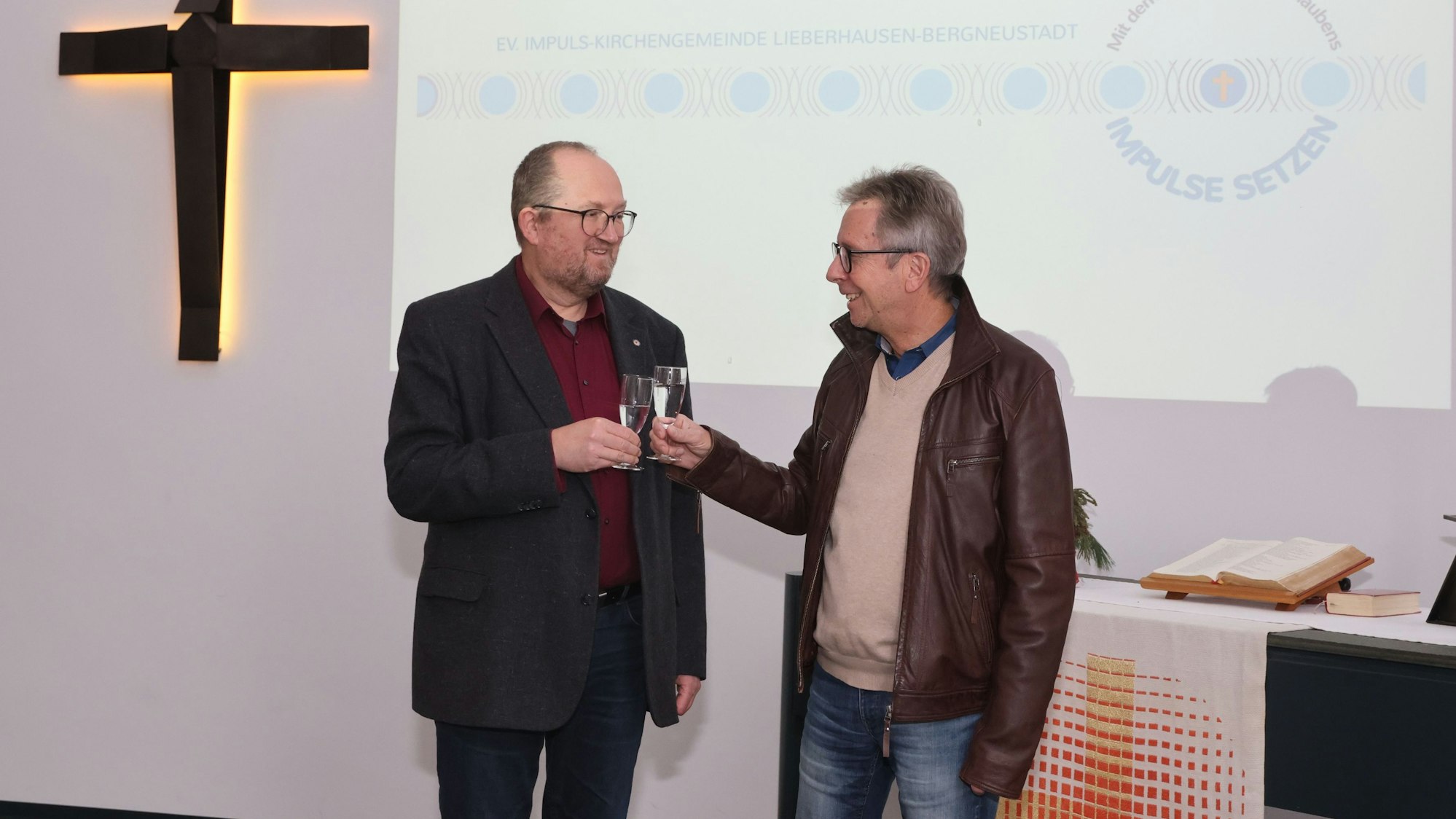 Zwei Pfarrer stoßen mit Sektgläsern an.