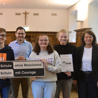 Schülerinnen und Schüler des Bad Münstereifeler St. Michael Gymnasiums zeigen das „Schule ohne Rassismus“-Plakat. Links steht Landrat Markus Ramers.