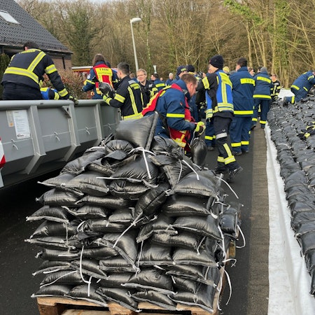 Einsatzkräfte verteilen Sandsäcke.