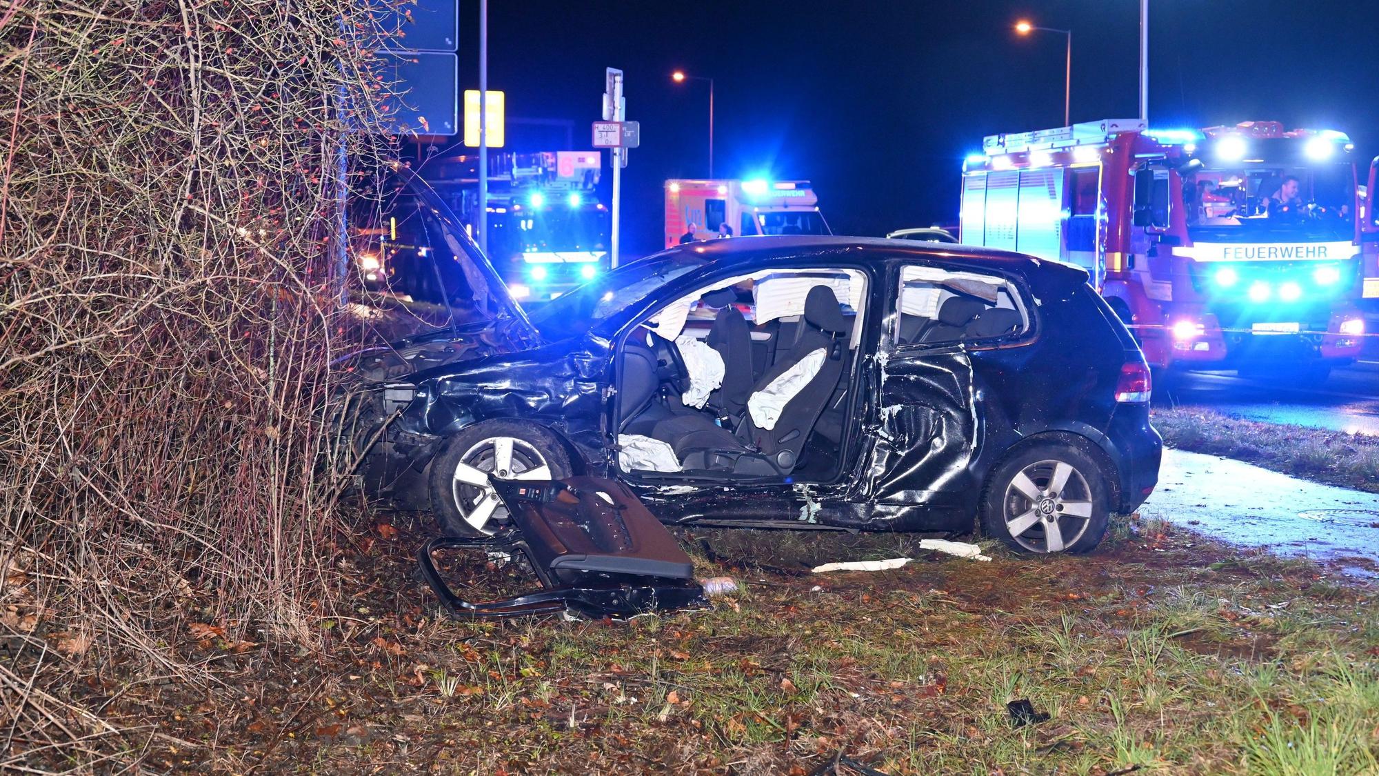 Ein VW Golf steht vor einem Gebüsch. Die Seite des Wagens ist zerstört, die Tür herausgerissen.