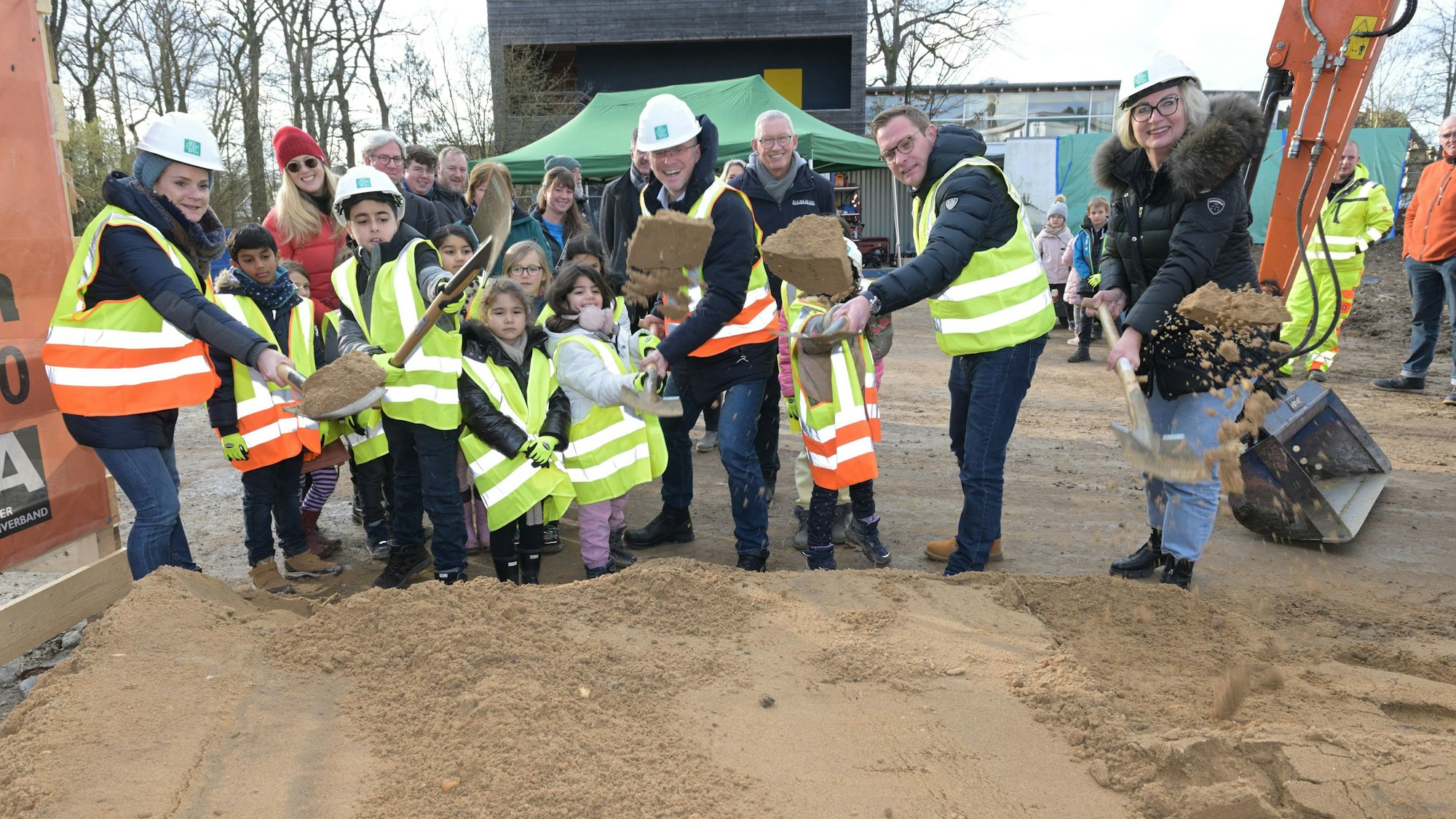 Erwachsene und Kinder schaufeln Erde.